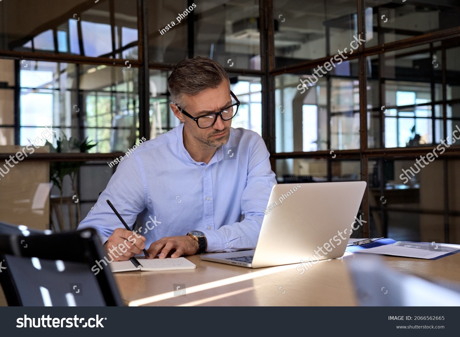 Mature business man executive manager looking at laptop computer watching online webinar training or having virtual meeting video conference taking notes, doing market research working in office. #2066562665