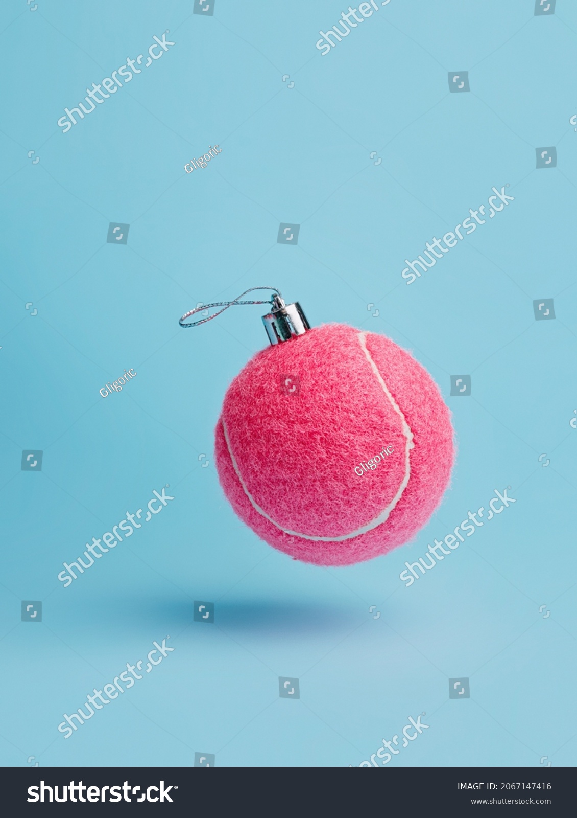 Creative Christmas layout made with flying pink tennis ball as a tree ornament vibrant red on pastel blue background. Minimal Xmas or New Year celebration concept. Minimal winter holidays idea.	 #2067147416