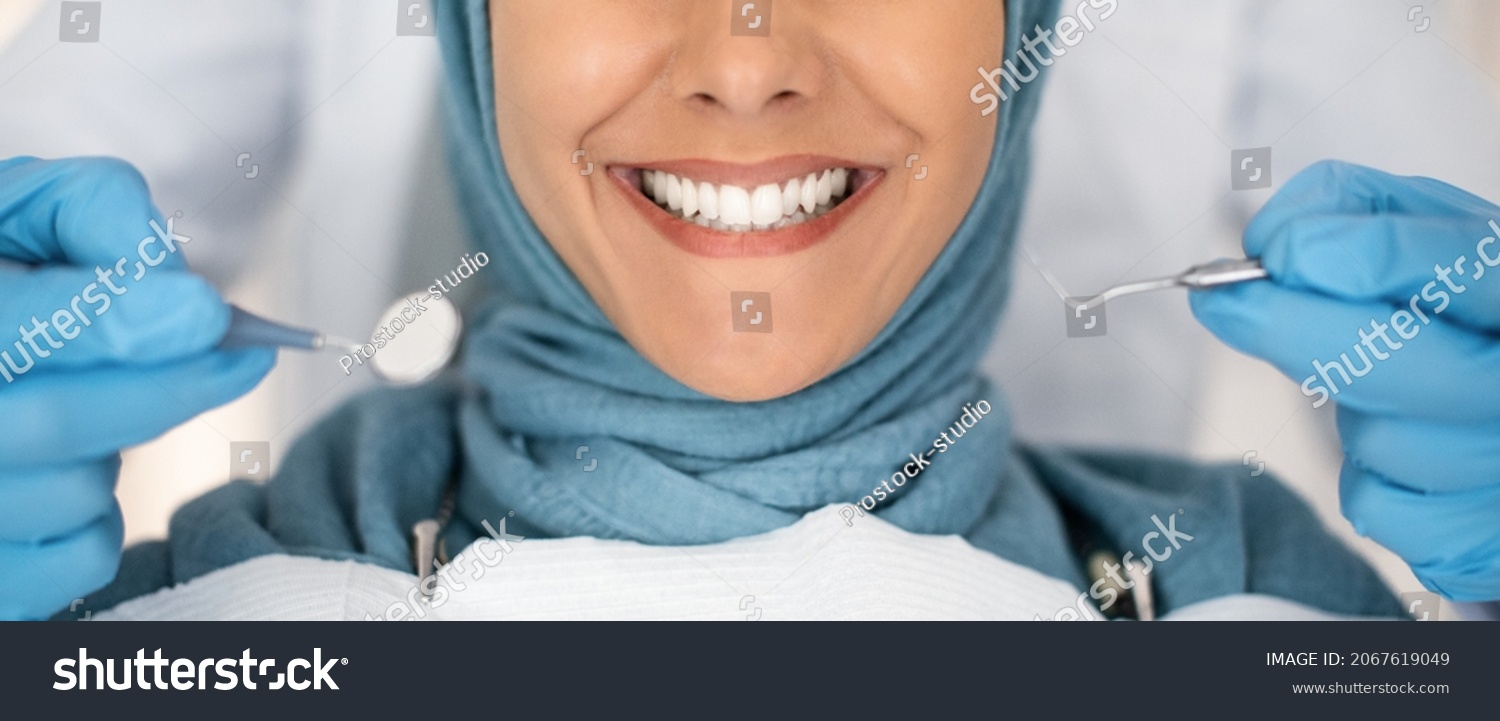 Dental Check Up. Closeup Shot Of Smiling Muslim Lady Getting Treatment In Stomatologic Clinic, Dentist In Blue Gloves Examining Teeth Of Islamic Lady In Hijab, Using Sterile Dental Tools, Cropped #2067619049