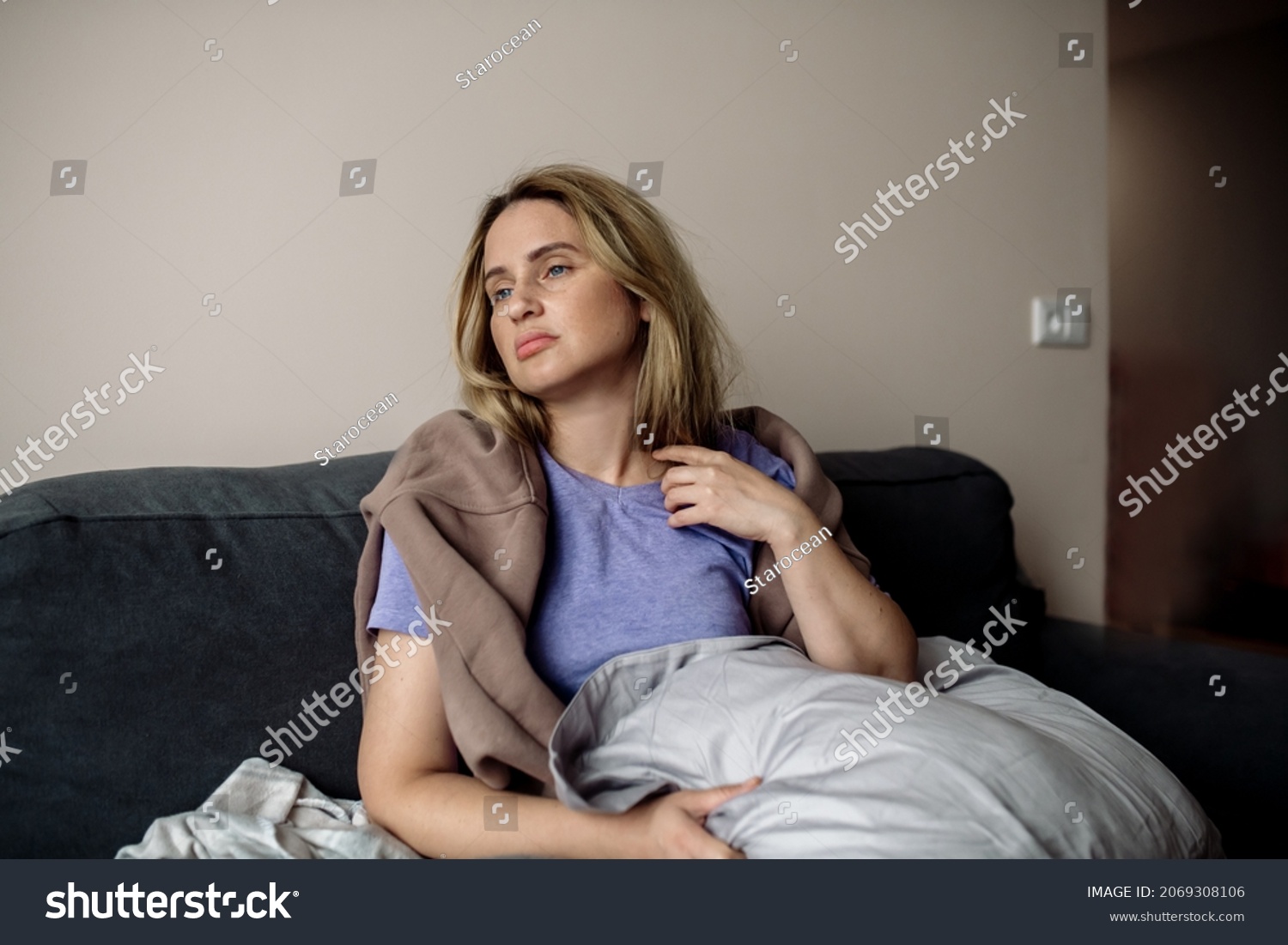 young woman with long covid syndrome - painful condition, headache, sitting on the couch at home #2069308106