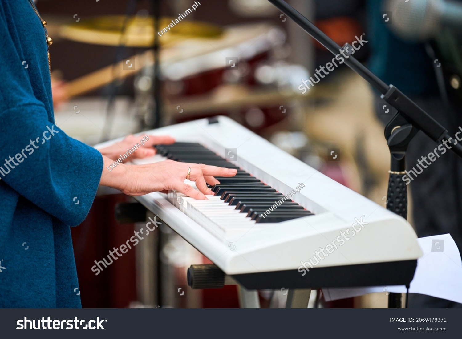 Musician woman playing on white synthesizer keyboard piano keys, female hands on synthesizer, close up. Musician playing synthesizer on concert stage, professional playing on synth piano #2069478371
