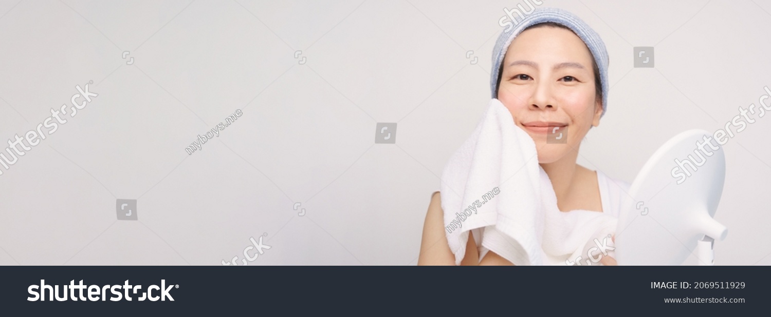 Banner of a beautiful asian woman wash and dry her face with soft white towel, she happily smiling for her soft and smooth facial skin. K beauty, No makeup, Daily skincare, Glowing, Cleansing, Fresh #2069511929