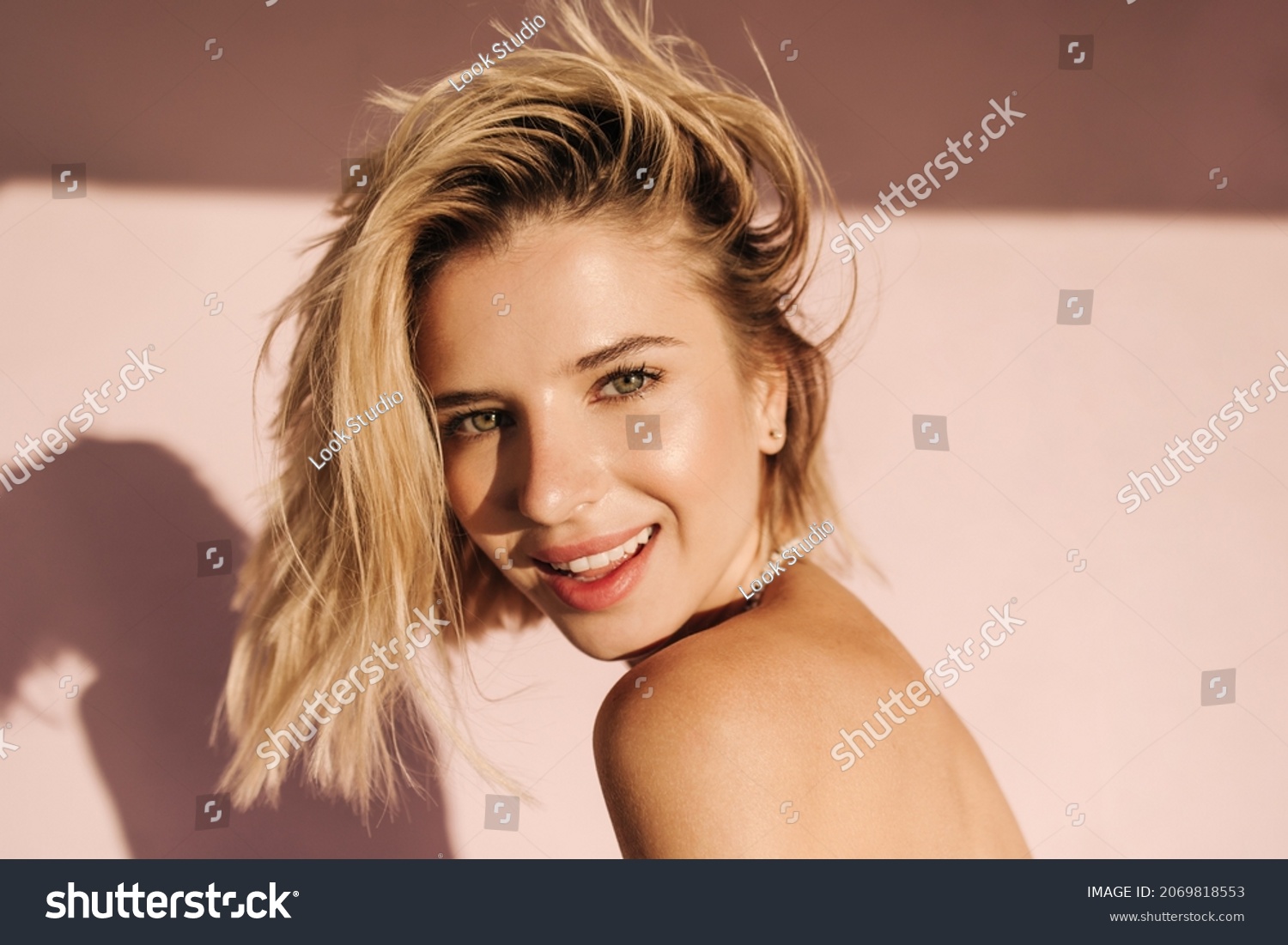 Close up portrait of fair skinned young woman looking at camera with mouth open. Blonde with short hair on one side on pink background with bare shoulders. People sincere emotions lifestyle concept. #2069818553