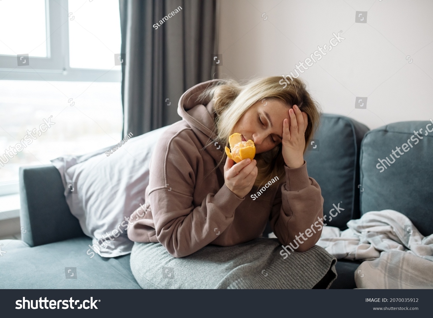 Long covid syndrome - increased fatigue, lack of strength, reduced immunity, memory problems and anosmia - loss of smell. Woman sniffs citrus fruits and does not smell #2070035912