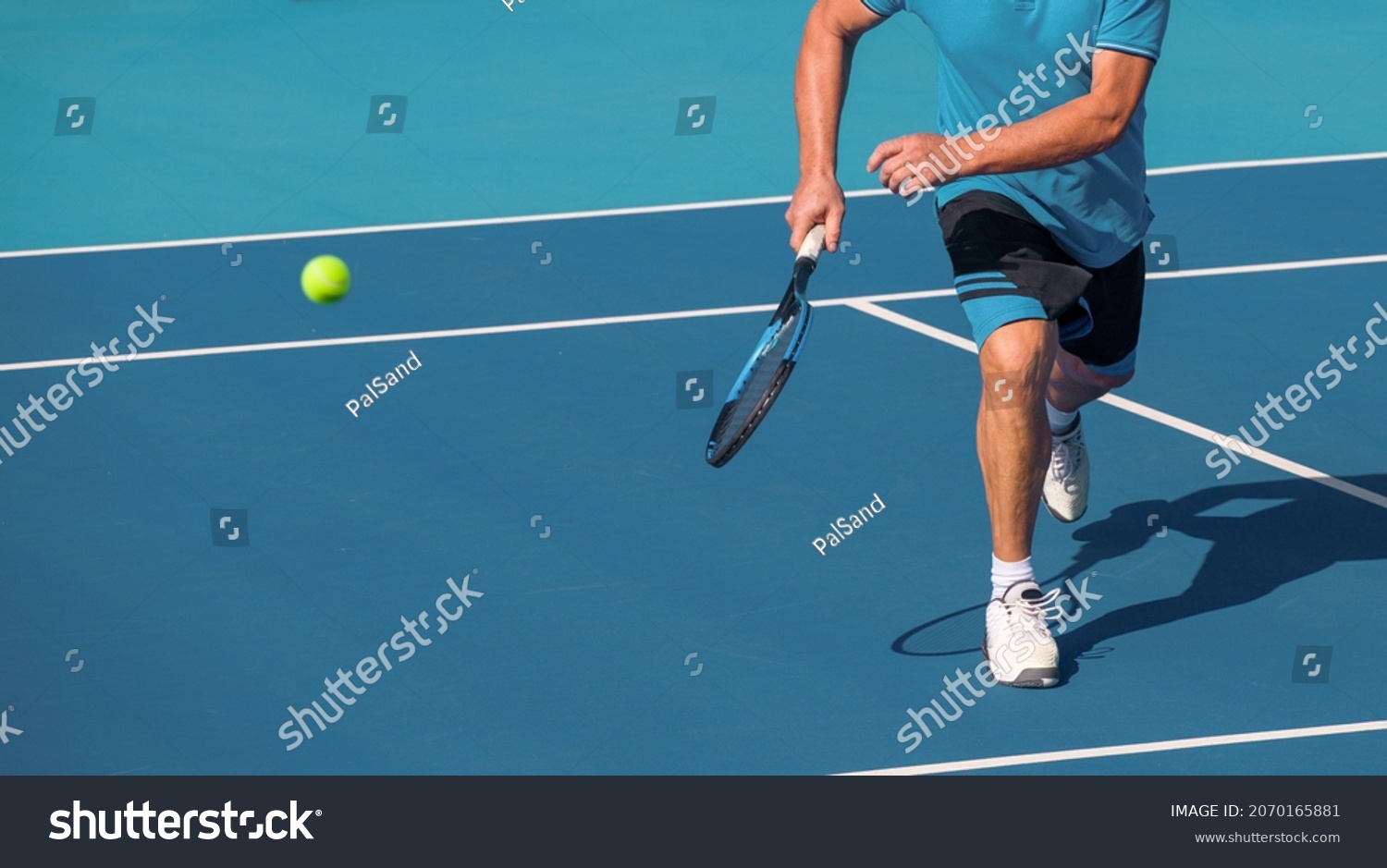 Tennis player playing tennis on a hard court on a bright sunny day #2070165881