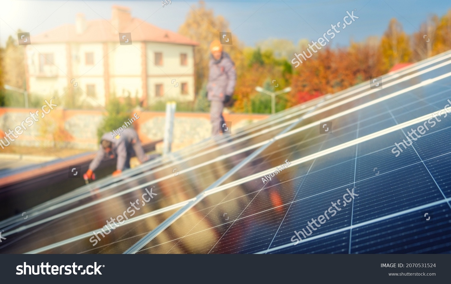 Solar panels on the roof of the building in the sun with workers. For alternative energy design. Selective focus. Blur #2070531524