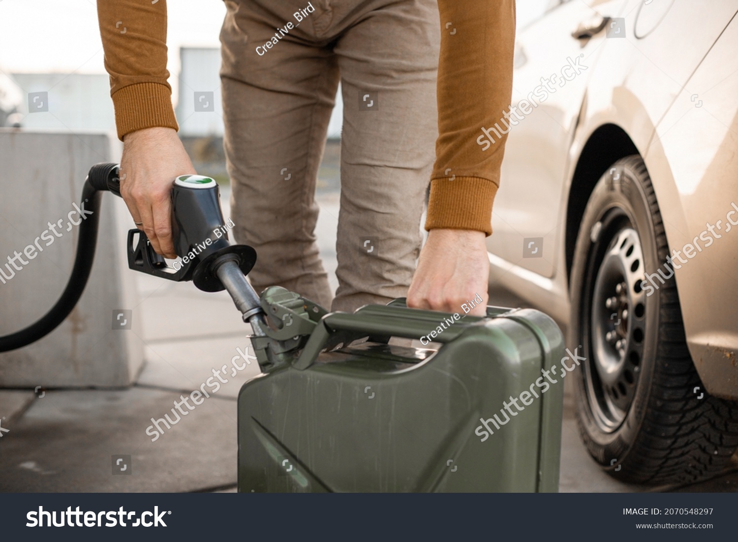 Man refilling canister with fuel on the petrol station. Close up view. Gasoline, diesel is getting more expensive. #2070548297