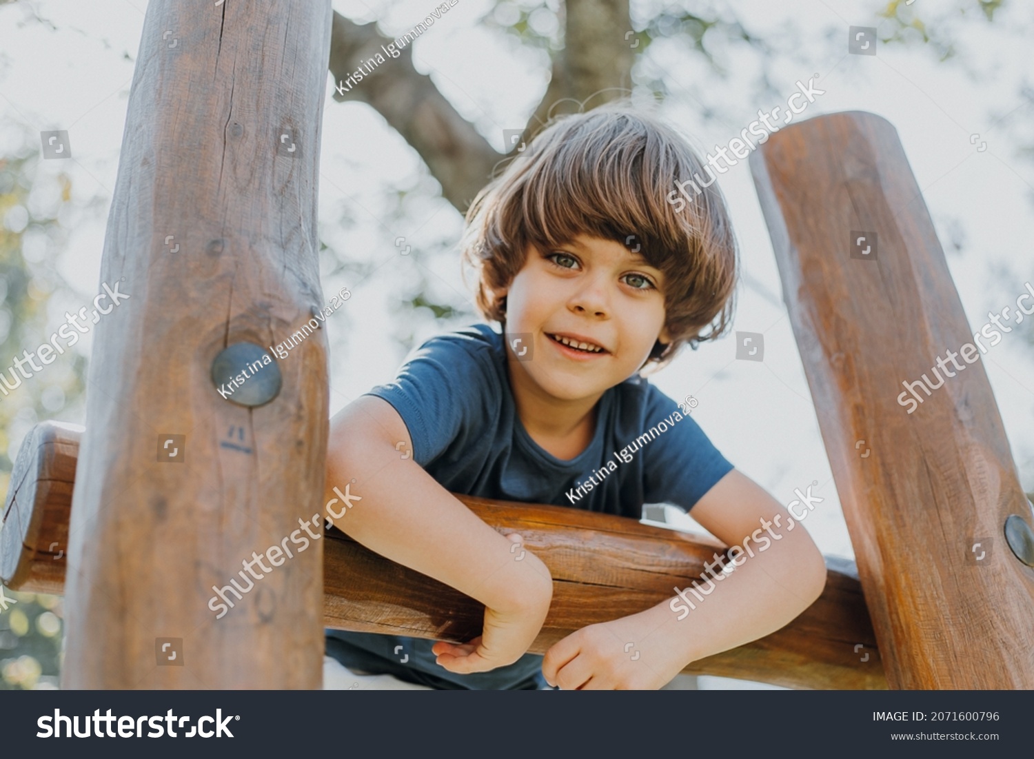 portrait of a smiling little brunette boy in a blue T-shirt playing outdoors. happy child, lifestyle. products for children. High quality photo #2071600796