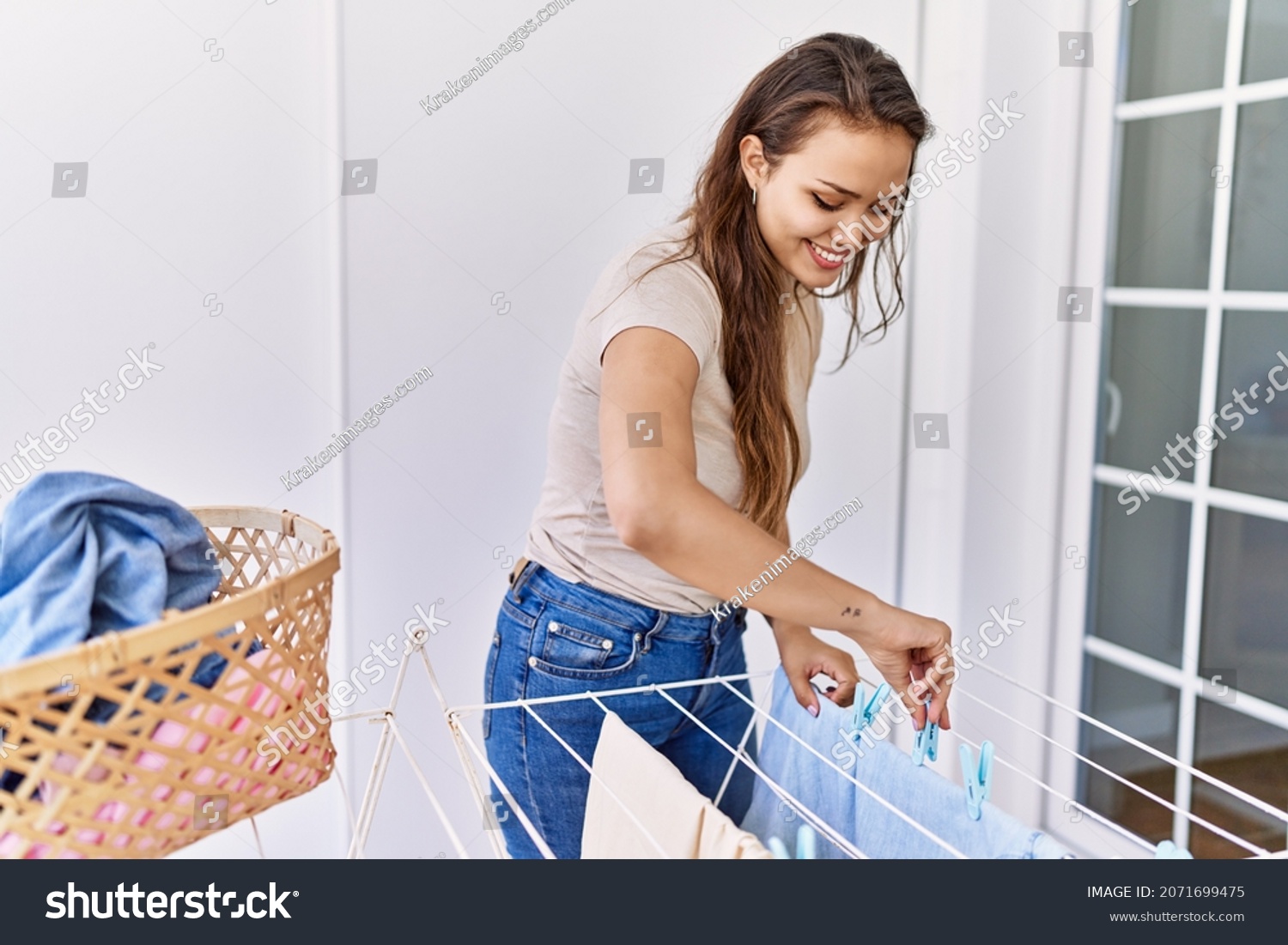 Young hispanic girl doing laundry hanging clothes at clothesline. #2071699475