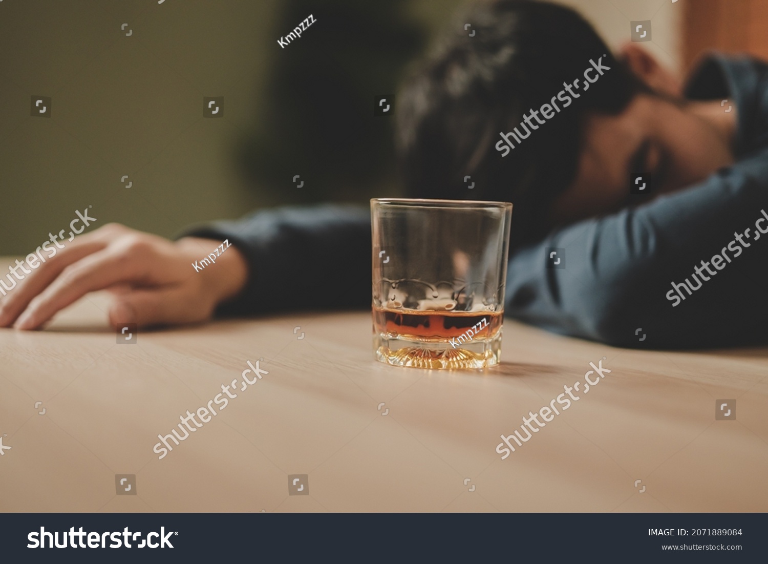 Alcoholism, depressed asian young man sleep on table while drinking alcoholic beverage, holding glass of whiskey alone at night. Treatment of alcohol addiction, suffer abuse problem alcoholism concept #2071889084