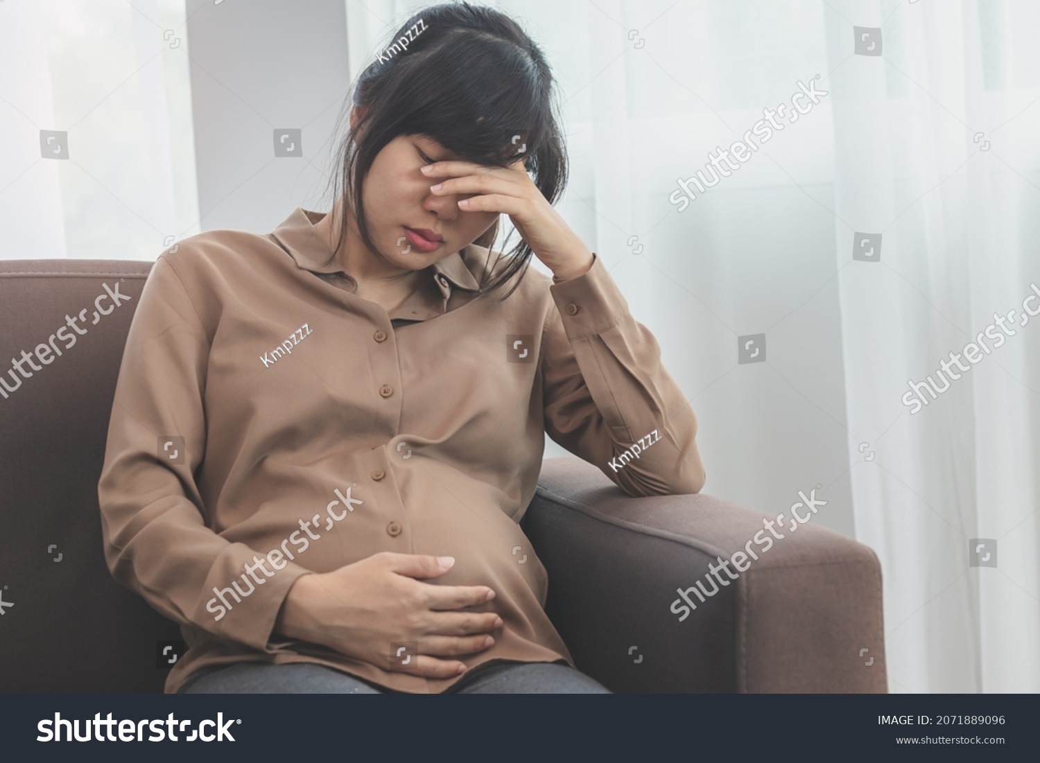 Asian young pregnant woman holding her belly while gynecologist notes the symptoms that the pregnancy is explaining about the unborn child. #2071889096