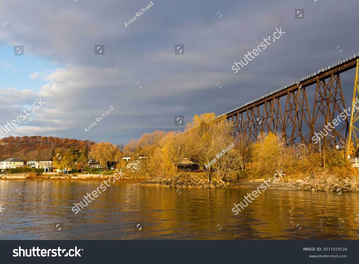 Golden hour landscape view of the Cap-Rouge River flowing into the St. Lawrence River, with a striking railway trestle bridge in the background, Cap-Rouge area, Quebec City, Quebec, Canada #2071919528