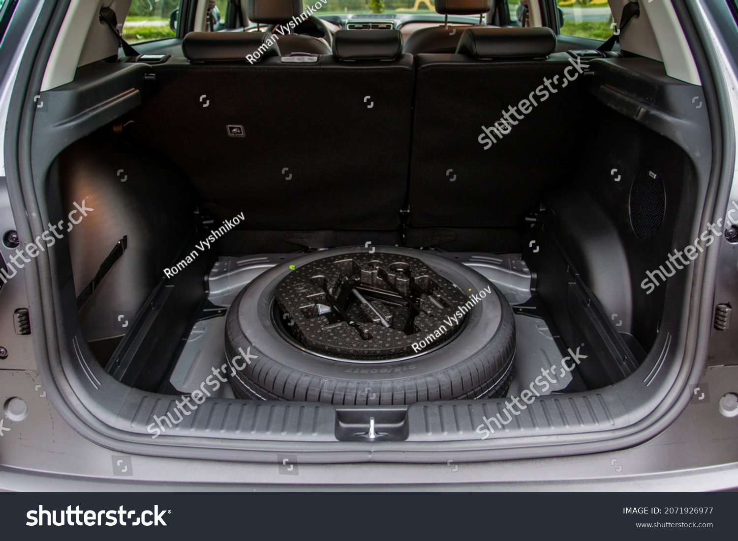 Spare wheel in the trunk of a modern car. Jack lifting and a spare tire in rear of car. #2071926977