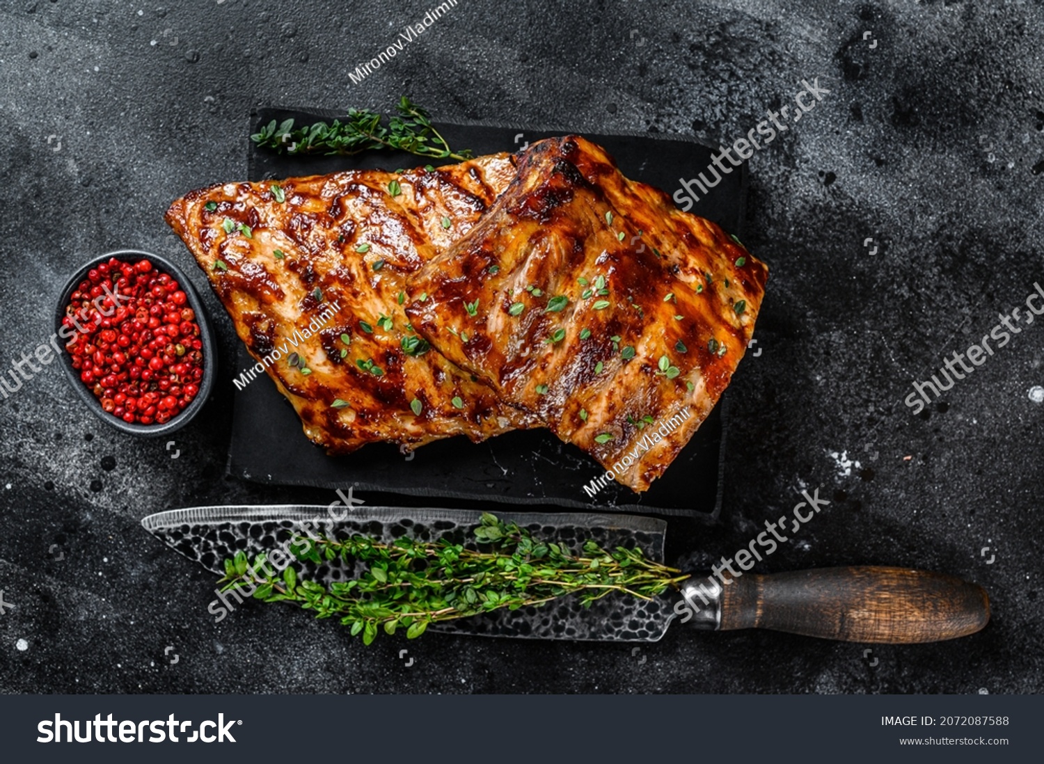 Barbecue pork rack spare ribs on a marble board. Black background. Top view #2072087588