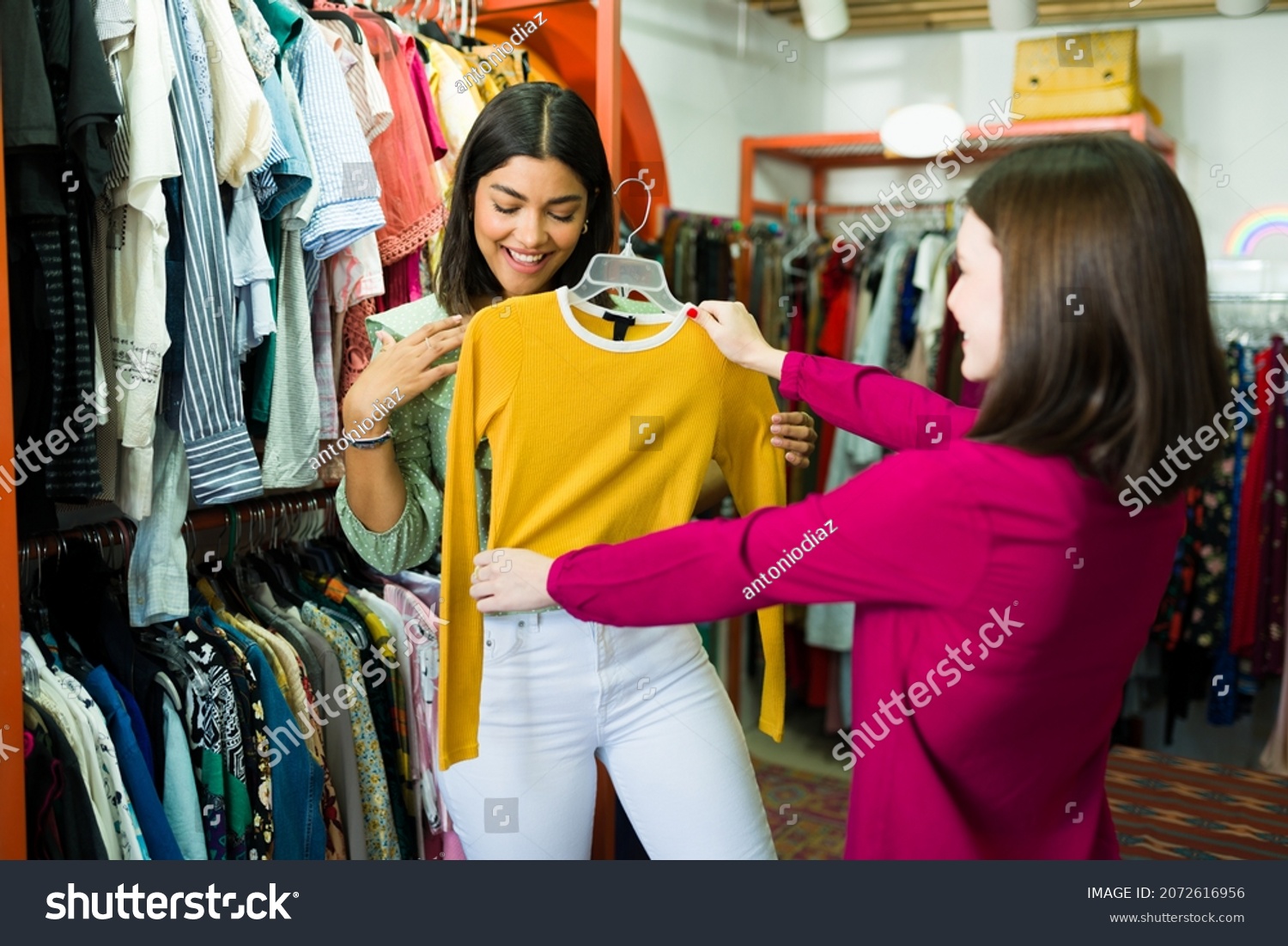 This looks good on you. Happy young woman buying second hand clothes at the clothing store #2072616956