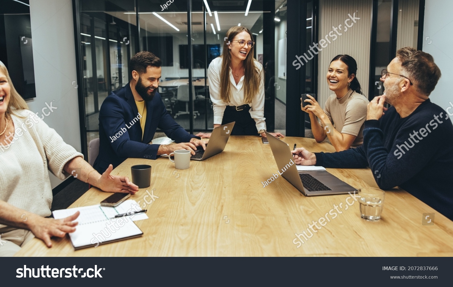 Colleagues laughing cheerfully during a meeting in a boardroom. Group of happy businesspeople enjoying working together in a modern workplace. Successful business professionals collaborating. #2072837666