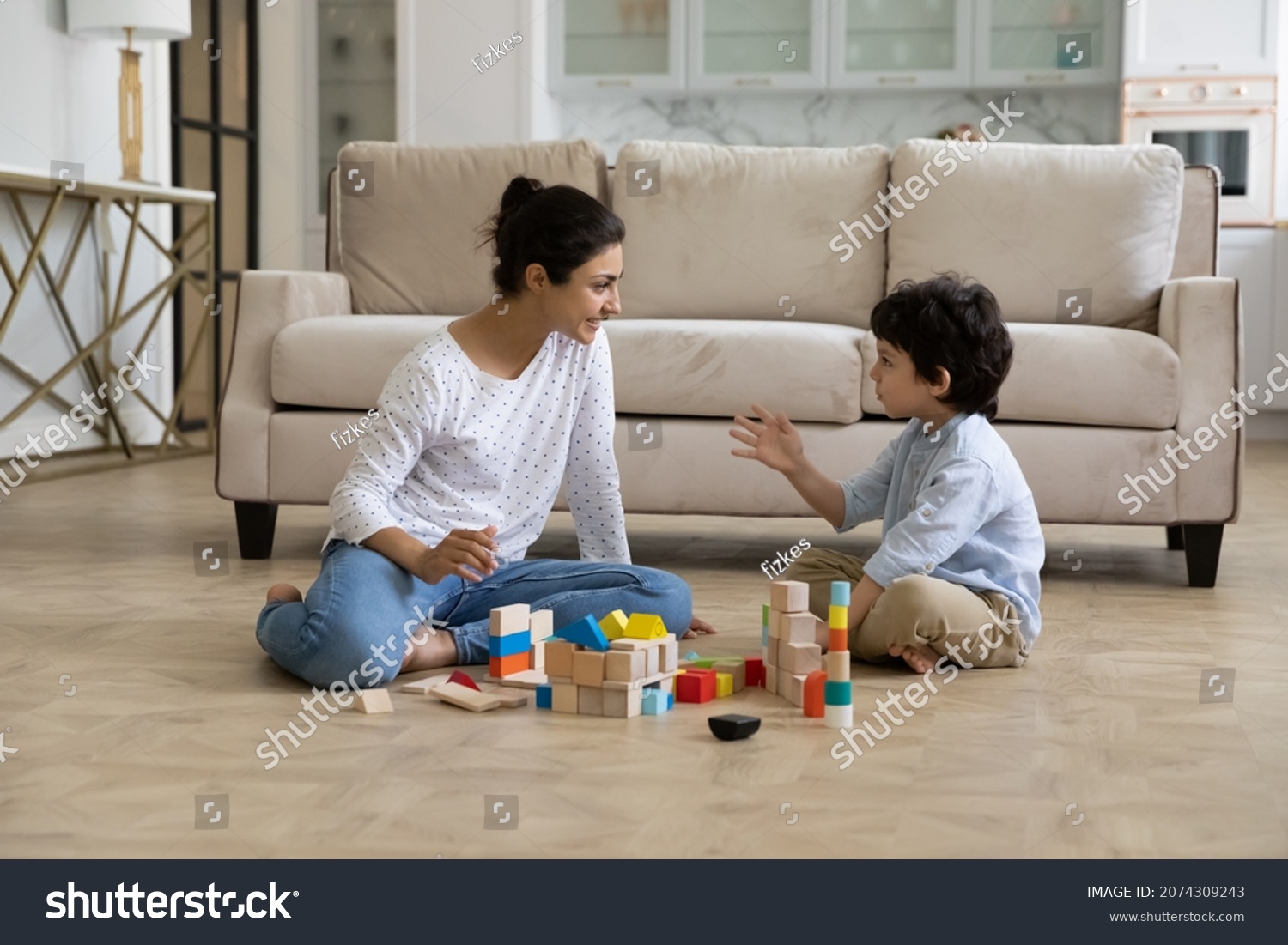 Loving young Indian mother and little son playing together on heating floor, building towers from toy construction bricks, talking, enjoying leisure, playtime, creative game. Motherhood concept #2074309243
