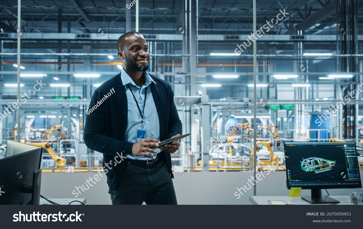 Car Factory Office: Successful Male Chief Engineer Overlooking Factory Production Conveyor. Automated Robot Arm Assembly Line Manufacturing Advanced High-Tech Electric Vehicles. Back View Shot #2075059453