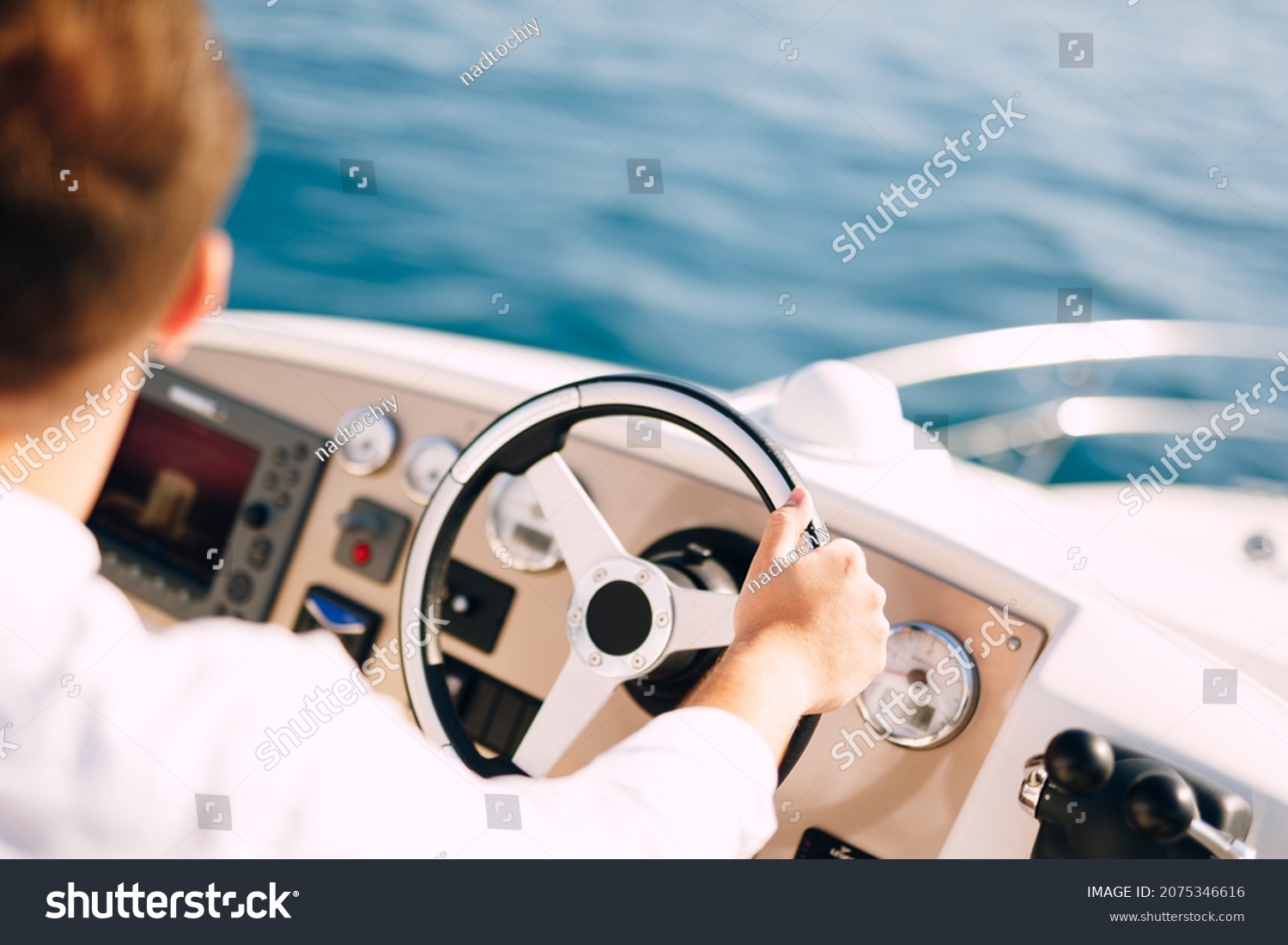 Man in a white shirt is driving a white motor boat. Close-up #2075346616