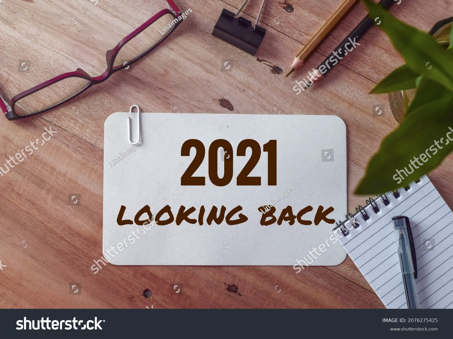 2021 looking back text on white card on office desk. Year highlights concept. Top view.  #2076275425
