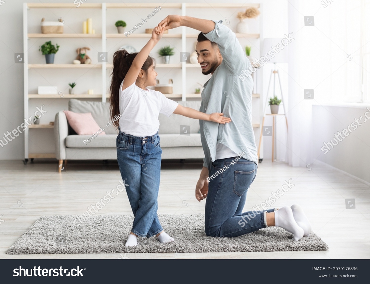 Loving arabic father dancing with his adorable little daughter at home, happy dad teaching pretty long-haired female kid dancing waltz, single father spending weekend with his child, copy space #2079176836