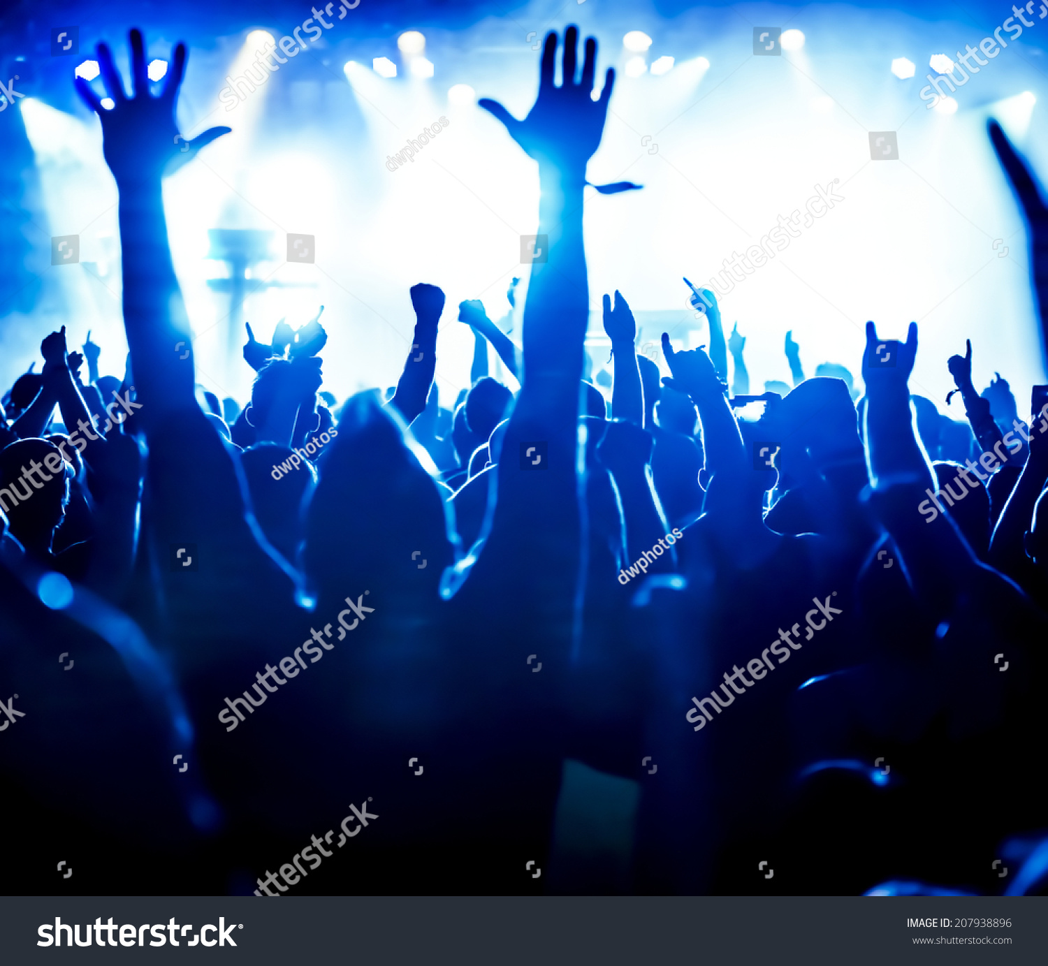 silhouettes of concert crowd in front of bright stage lights #207938896