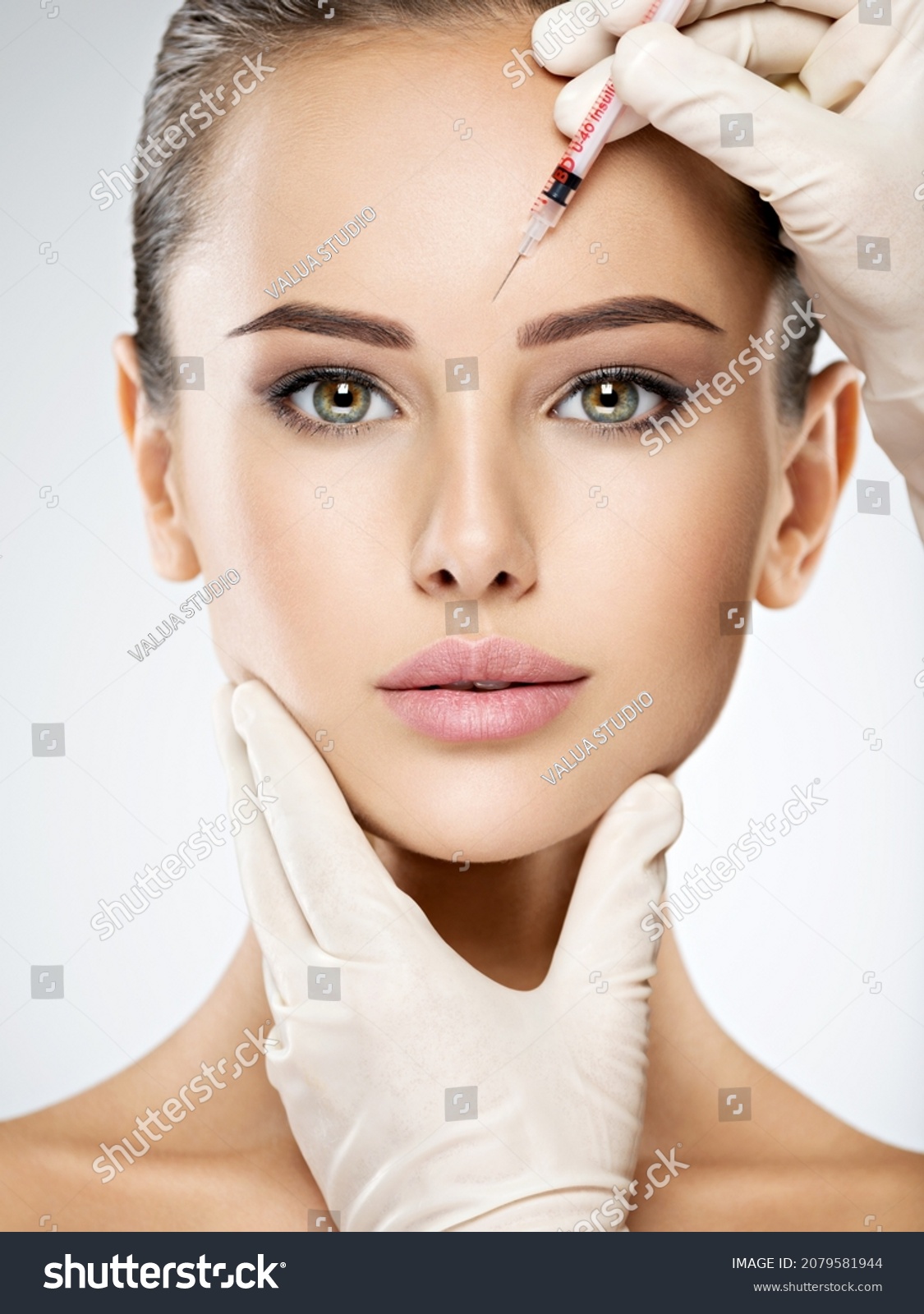 Portrait of young Caucasian woman getting botox cosmetic injection in forehead. Beautiful woman gets botox injection in her face. #2079581944