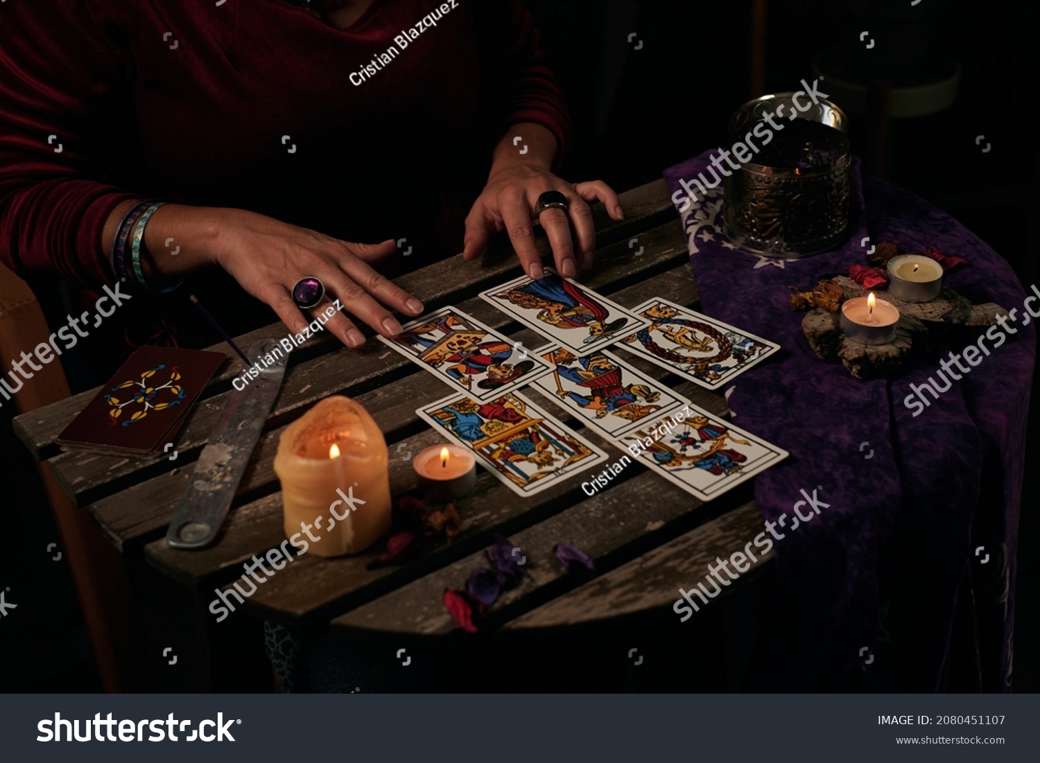 Pythoness reads tarot cards on a table with candles #2080451107