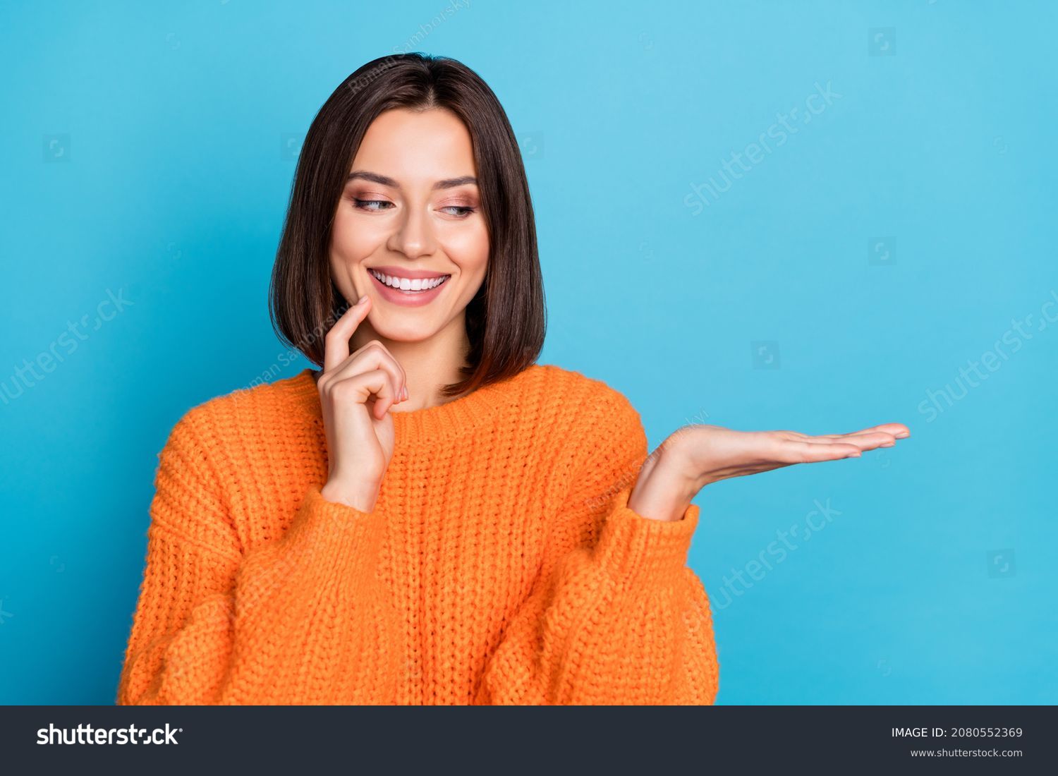 Portrait of attractive cheerful girl holding on palm copy space choosing idea isolated over bright blue color background #2080552369