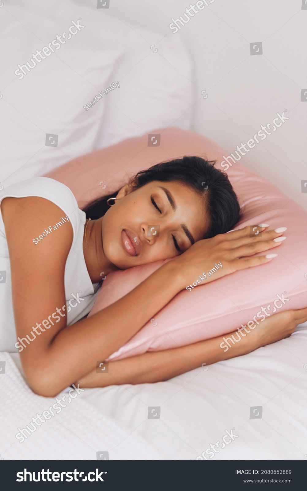 Beautiful Indonesian girl lying on a pink pillow with a silk pillowcase.
 #2080662889