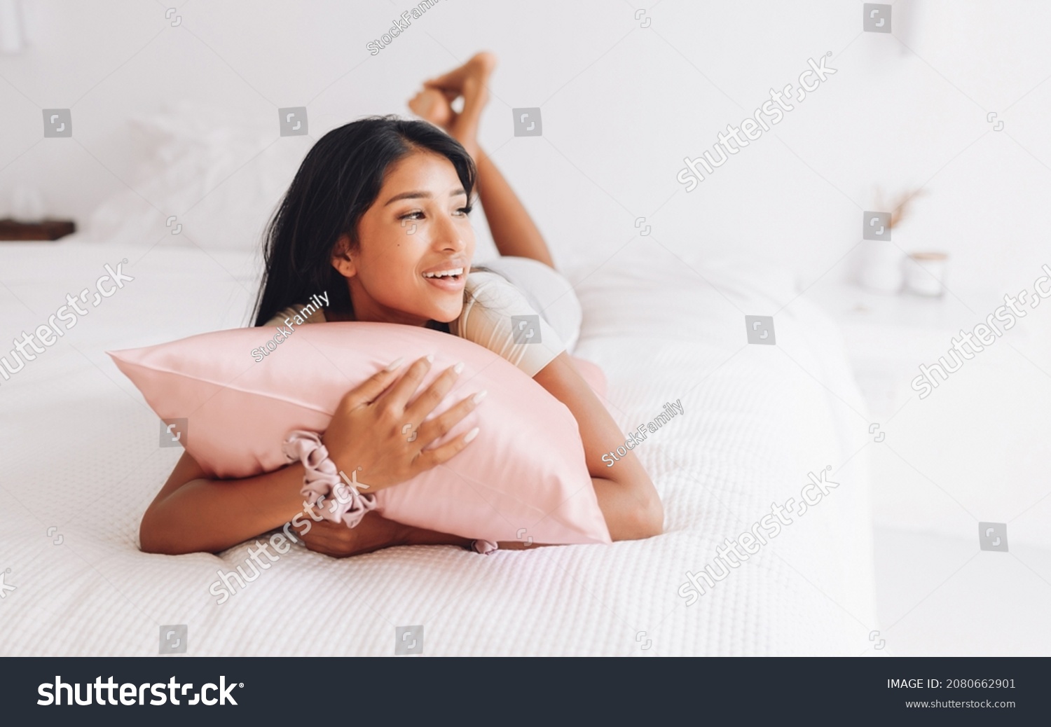 Beautiful Indonesian girl lying on a pink pillow with a silk pillowcase.
 #2080662901