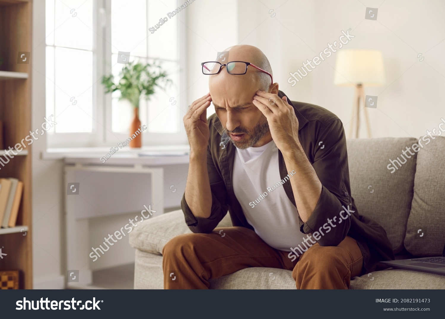 Man starts to realise. Confused thinker sitting on sofa with laptop computer at home, thinking, trying to understand situation, find answer, remember difficult word, analyze or resolve complex problem #2082191473
