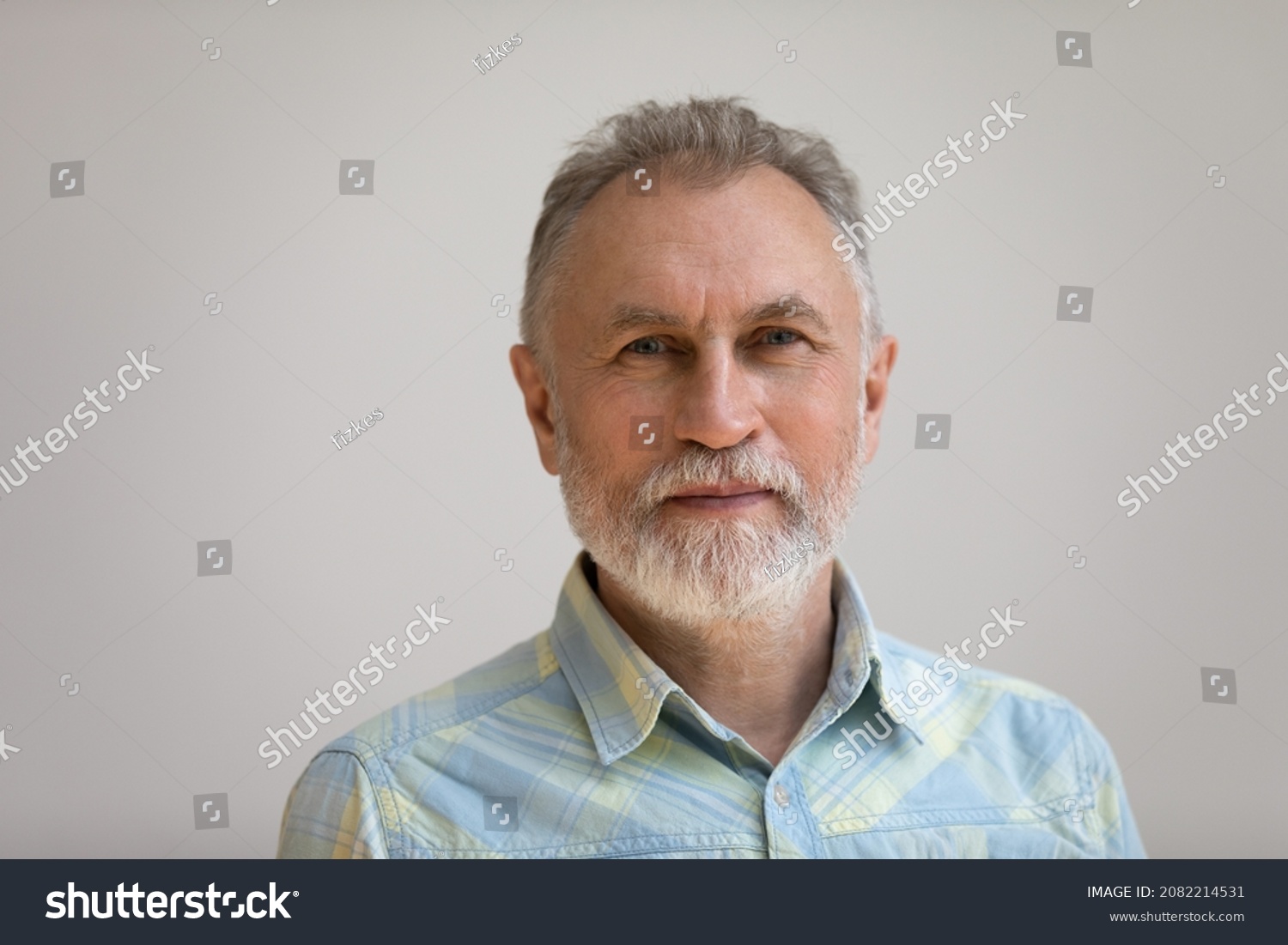 Serious older man in casual with beard head shot portrait. Grey haired retiree, pensioner posing, standing isolated against white wall background. Close up male portrait, elderly age concept #2082214531
