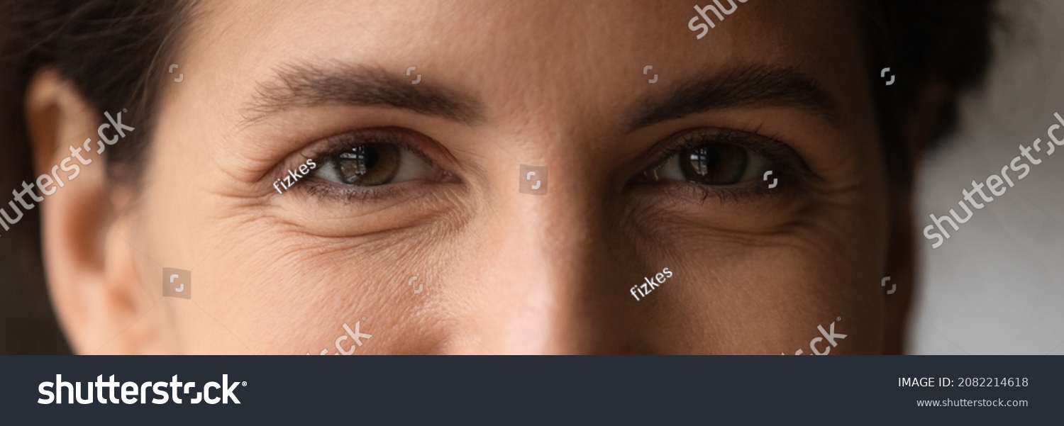 Close up cropped shot of young smiling woman face with beautiful eyes. Good vision and eye care. Contact lenses. Natural female beauty. Eye contour treatment cosmetic line. Wide horizontal web banner #2082214618