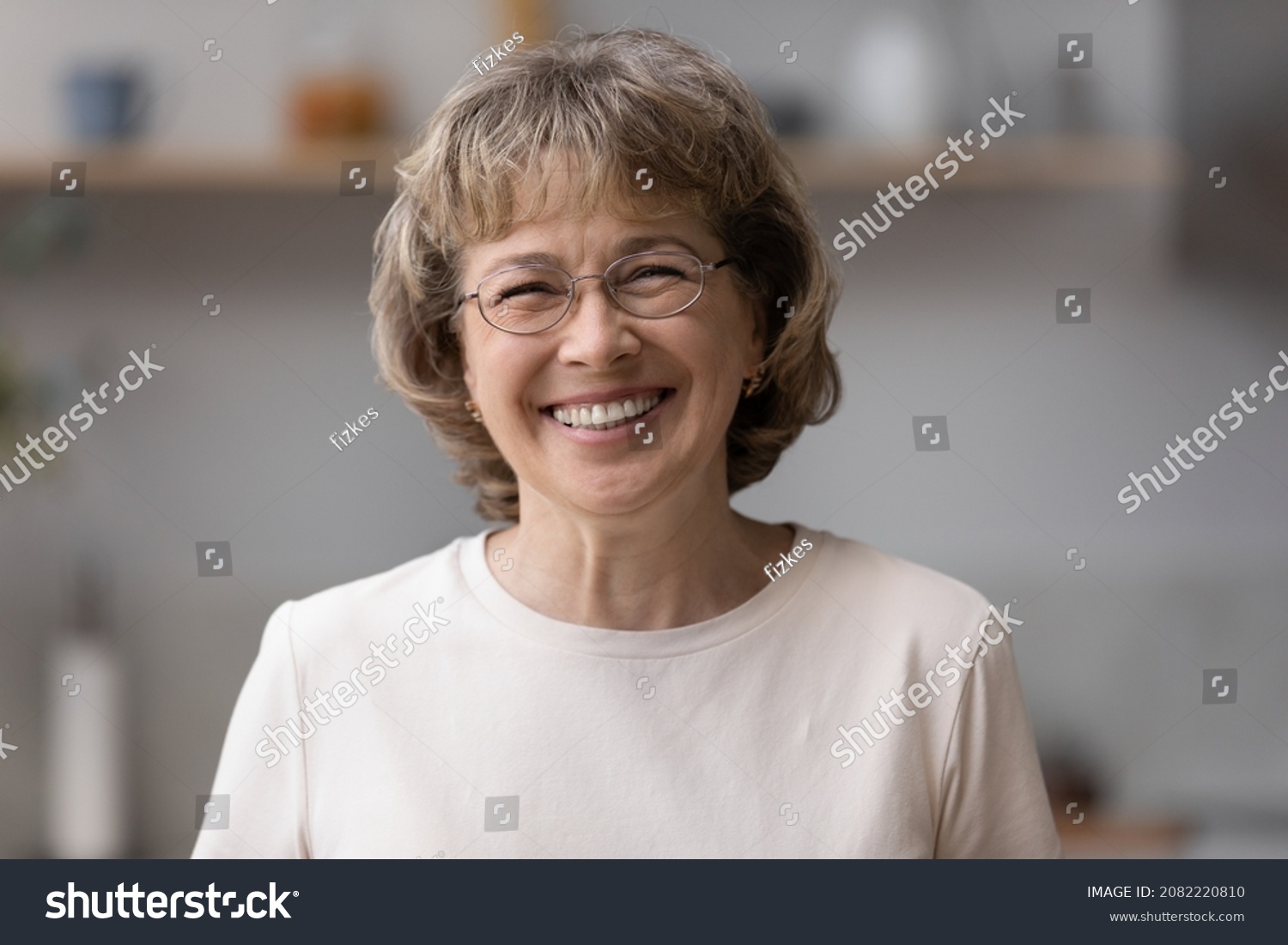 Happy older mature 60s woman indoor head shot portrait. Cheerful elder lady wearing eye glasses, casual, looking at camera with toothy smile, posing at home, laughing. Video call screen #2082220810