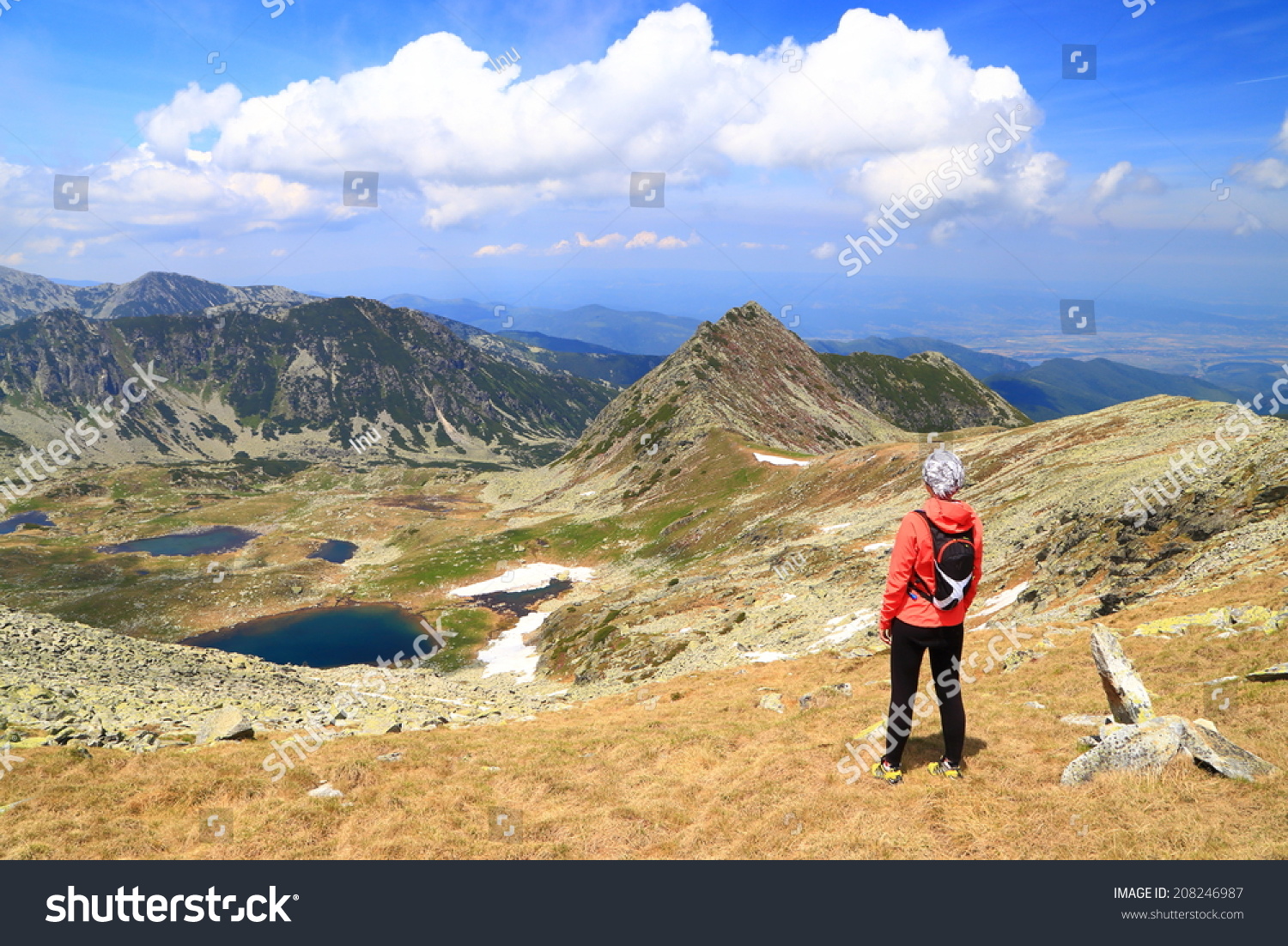 Beautiful mountain landscape with young woman standing and admiring the view #208246987