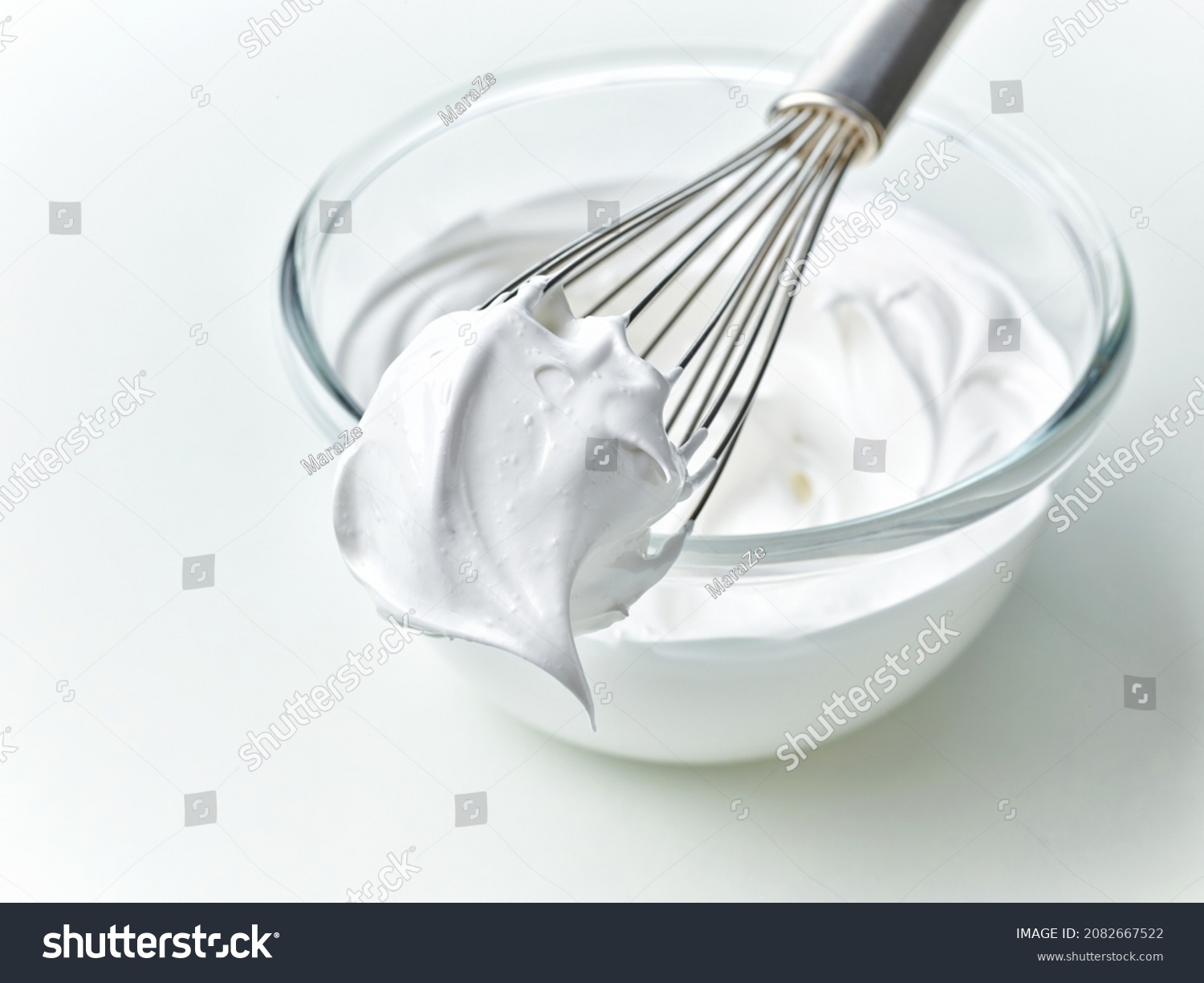 glass bowl of whipped egg whites cream on white kitchen table background #2082667522
