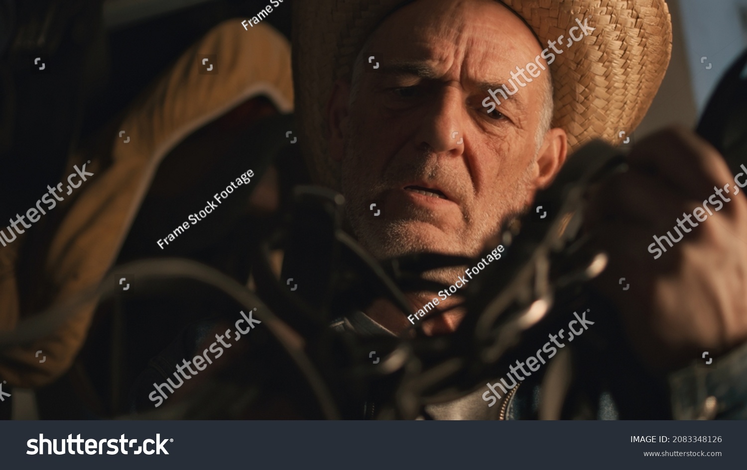 Elderly farmer inspecting bridle in stable #2083348126