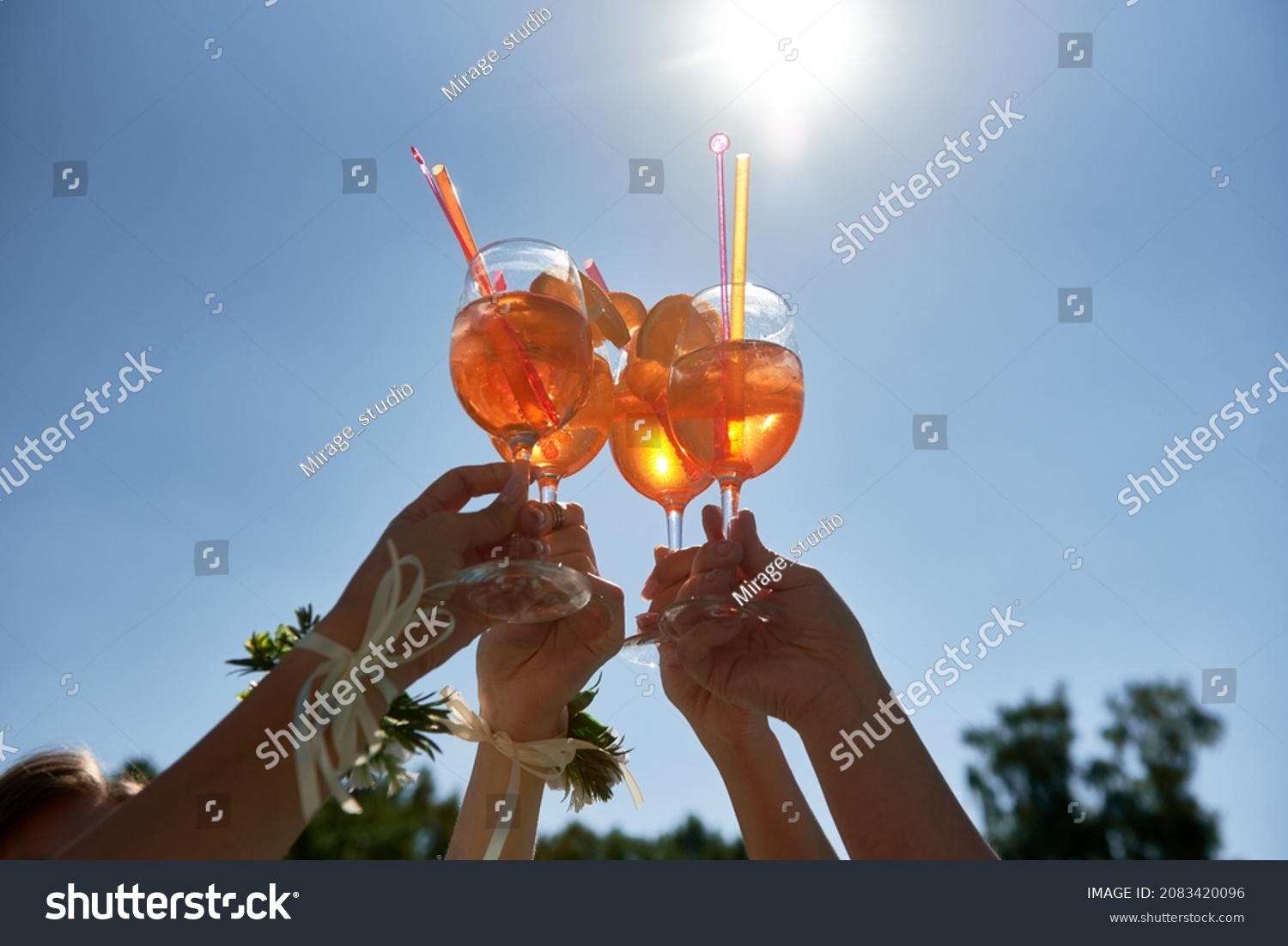 Women hands toasting with aperol spritz cocktails on summer party on blue sky background, copy space. Event celebration concept. Traditioanal italian aperitif. #2083420096