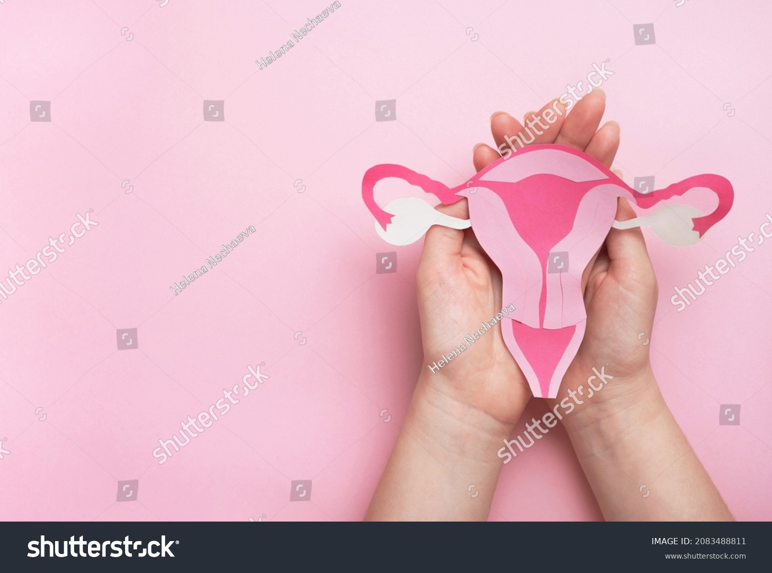 Women's health, gynecology and reproductive system concept. Woman hands holding decorative model uterus on pink background. Top view, copy space #2083488811