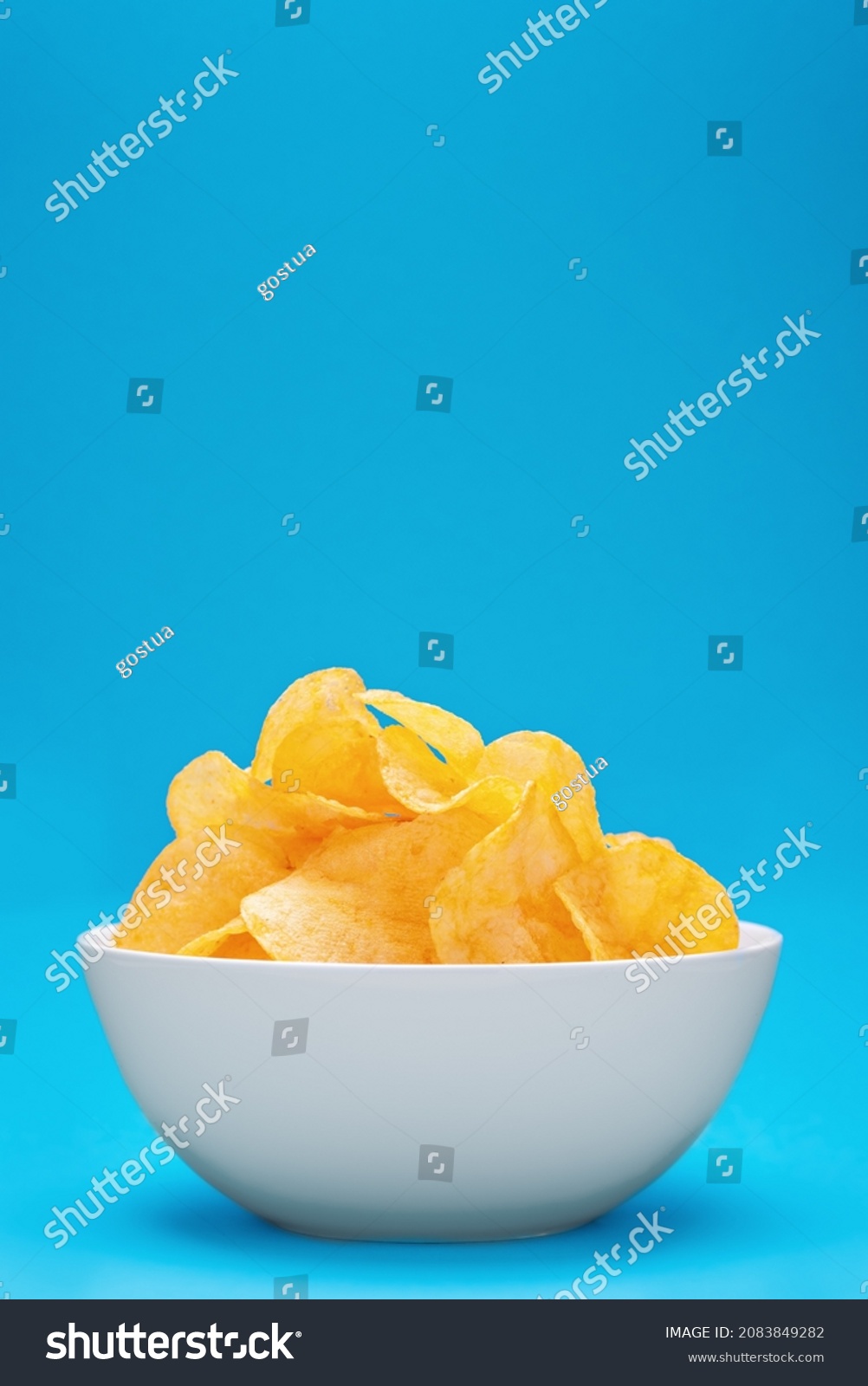 Potato chips or crisps in white bowl on blue background #2083849282
