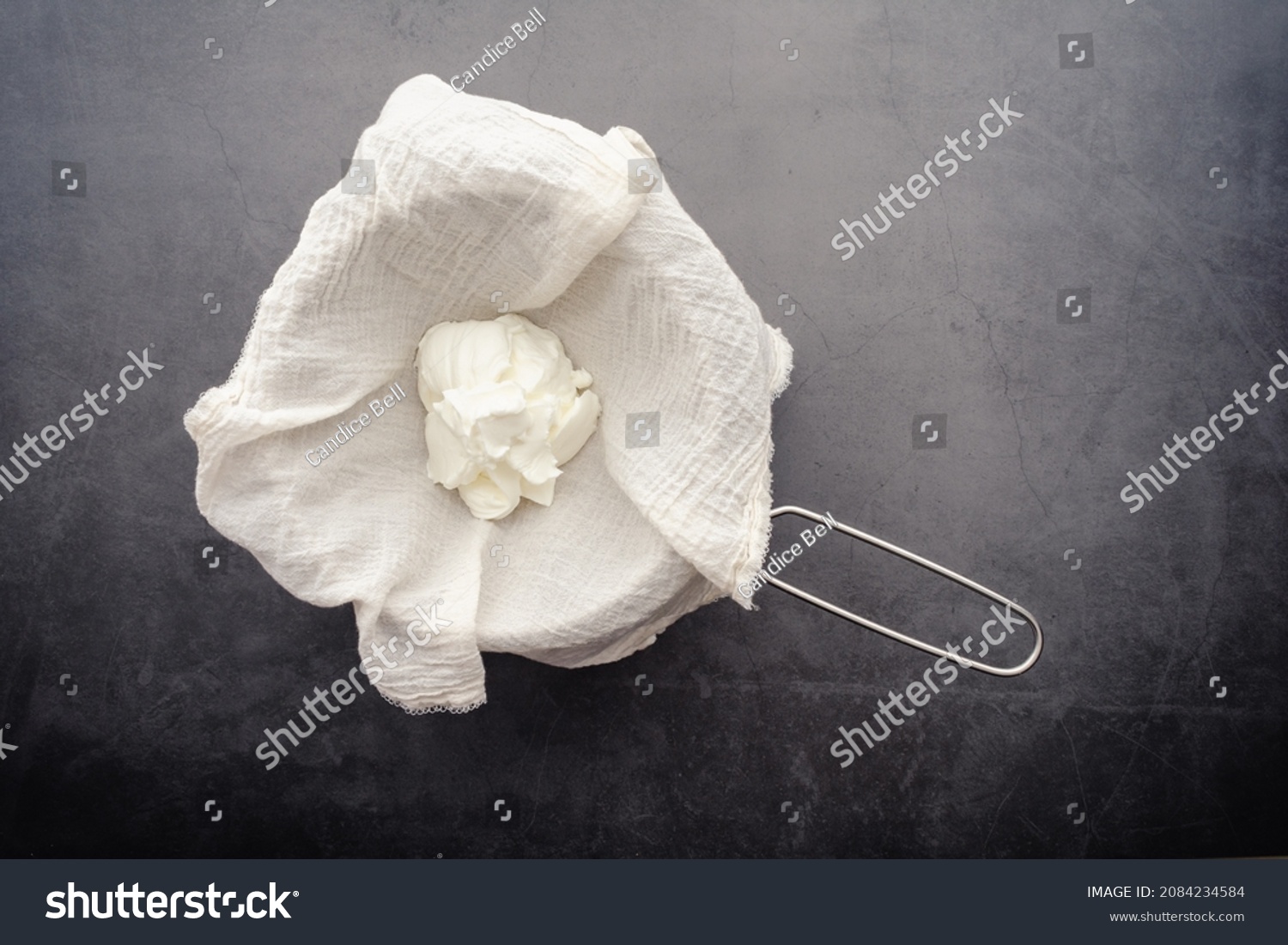 Making Labneh Cheese in a Cheesecloth Lined Strainer: Straining yogurt mixed with lemon juice and salt to make cheese #2084234584