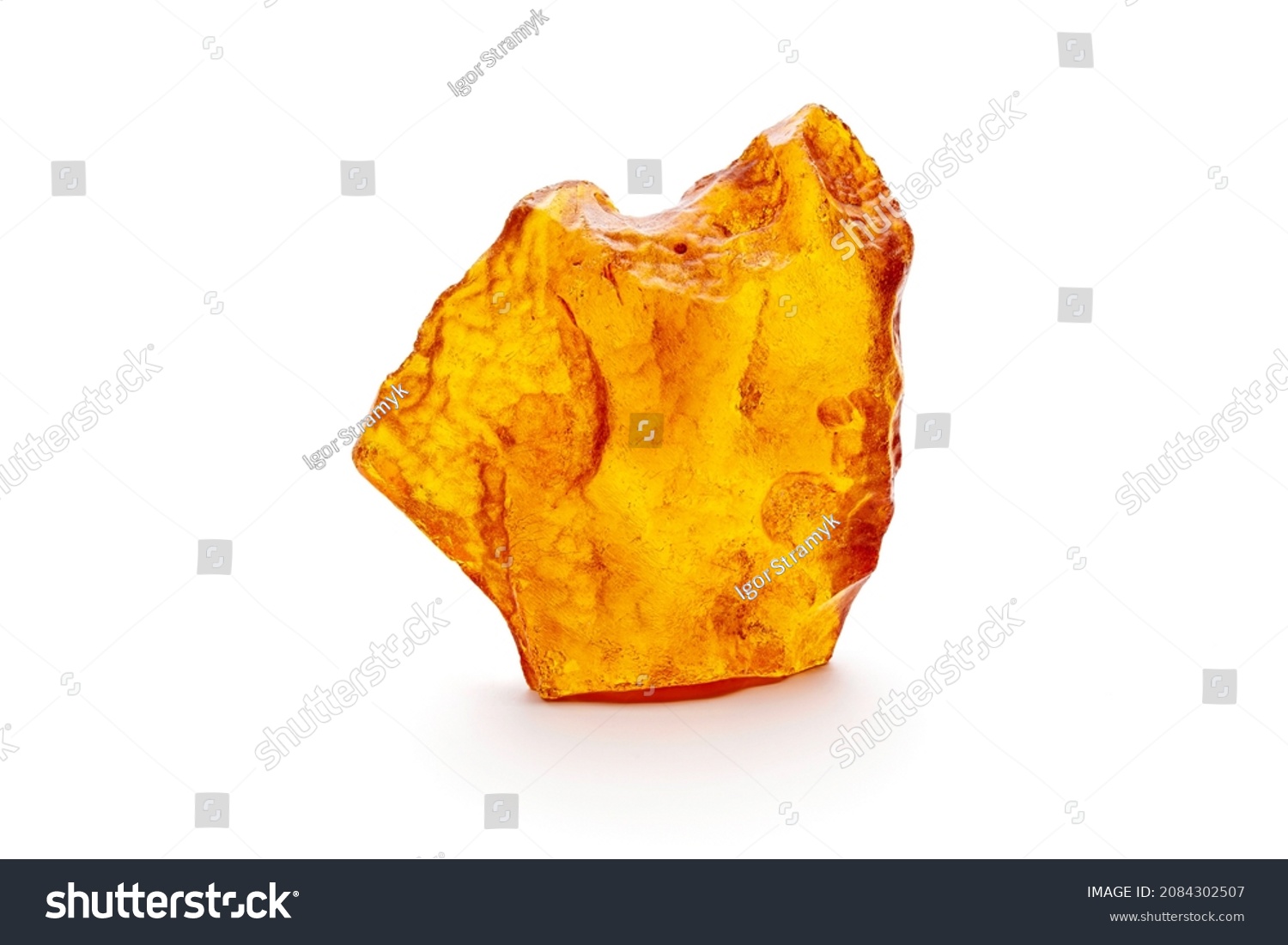 A piece of yellow opaque natural amber classification color Clear Succinite, has superficial cracks on its surface. Placed on white background. #2084302507