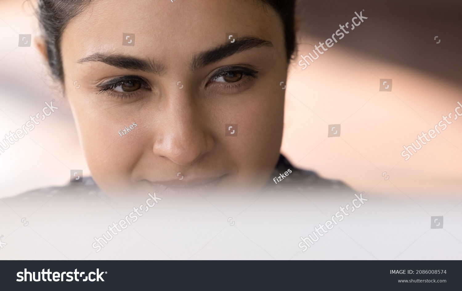 Satisfied smiling Indian employee working at computer banner close up face portrait. Young millennial business woman sitting at monitor, looking at display, watching, reading content #2086008574
