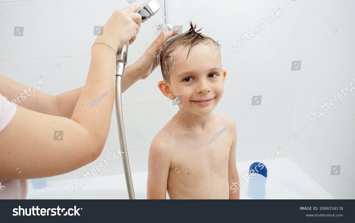 Young smiing boy looking in camera while mother washing his head in shower #2086558138