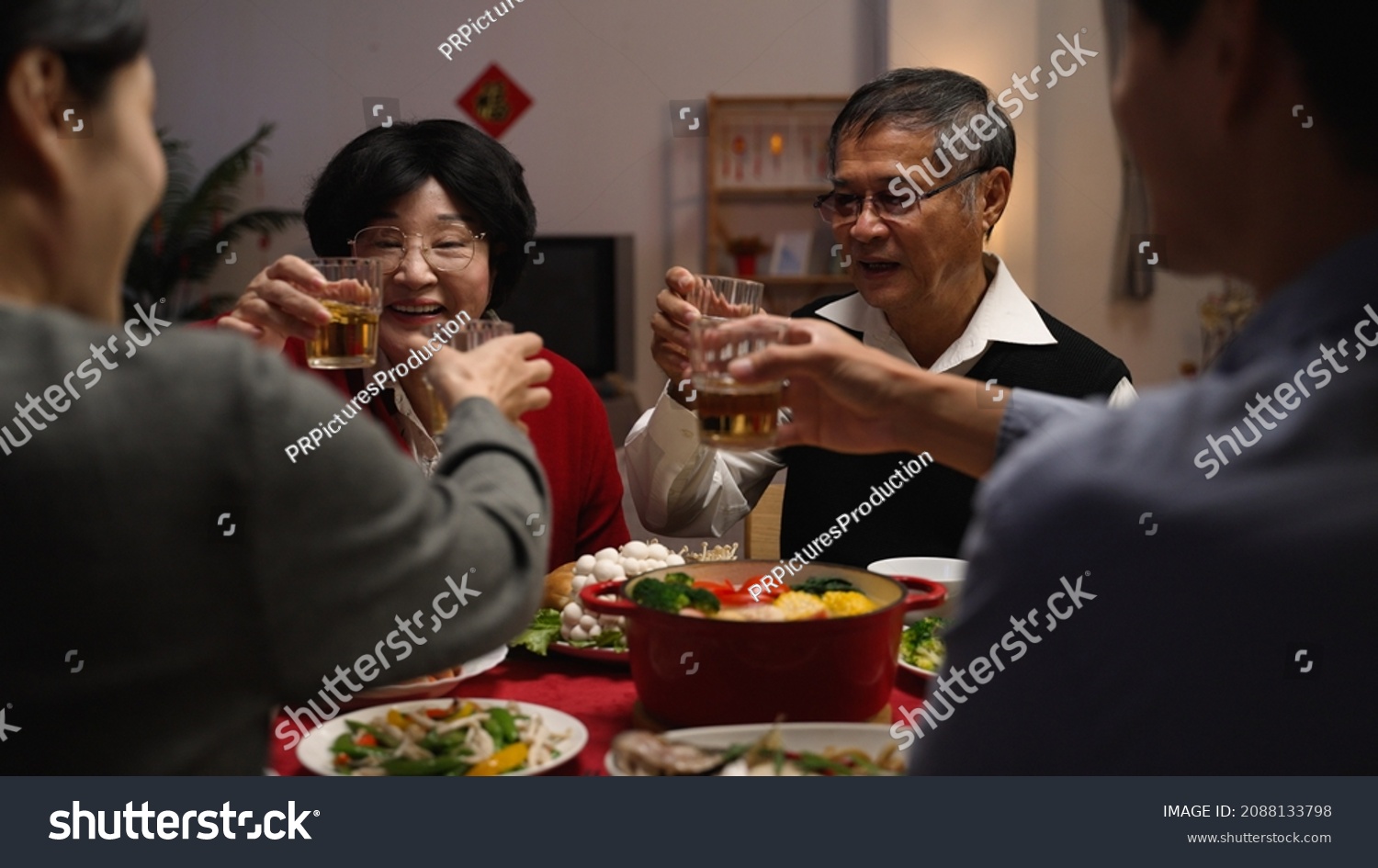 over shoulder shot with selective focus senior couple grandfather and grandmother making toast to family members, celebrating spring festival while having big meal on new year's eve #2088133798