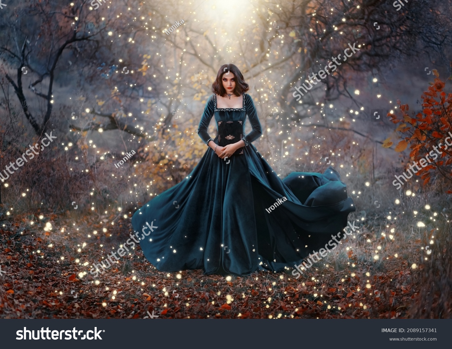 Gothic fantasy woman witch holding magic book hands. Long black velvet medieval vintage dress flies wind. Girl conjures. Bright divine light glow sparkles magic circle around lady. Autumn forest tree #2089157341