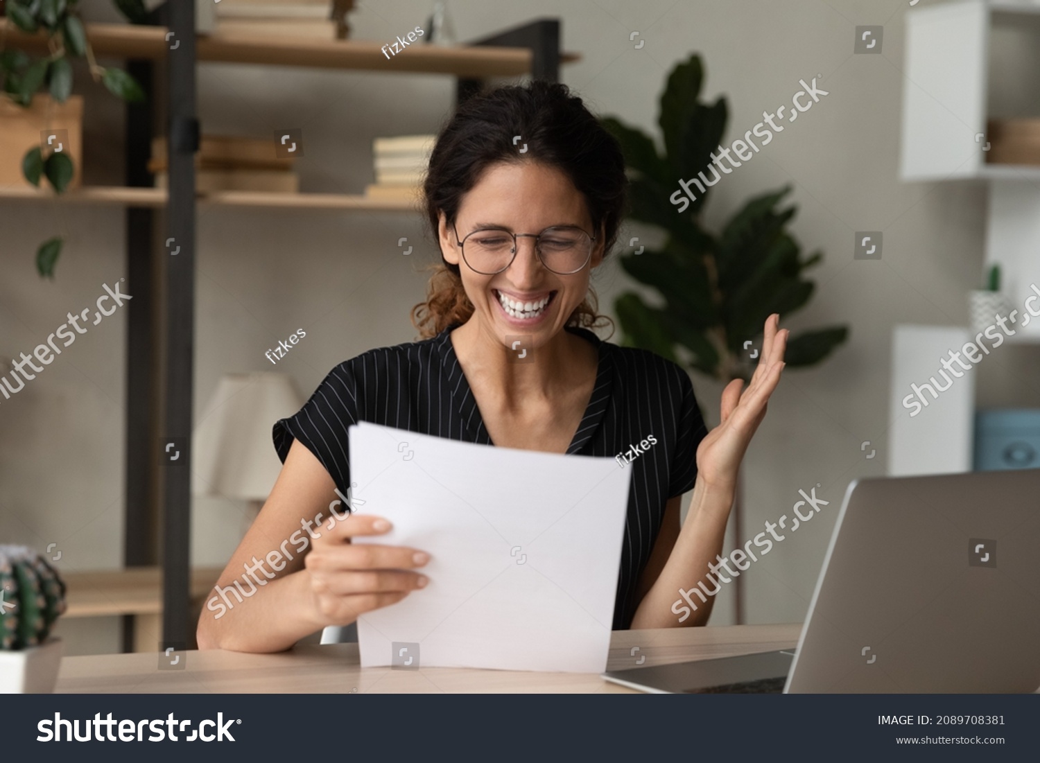 Overjoyed young Hispanic woman feel euphoric read good news in paper letter at home office. Smiling Latino female triumph get promotion offer or notice in paperwork correspondence. Success concept. #2089708381