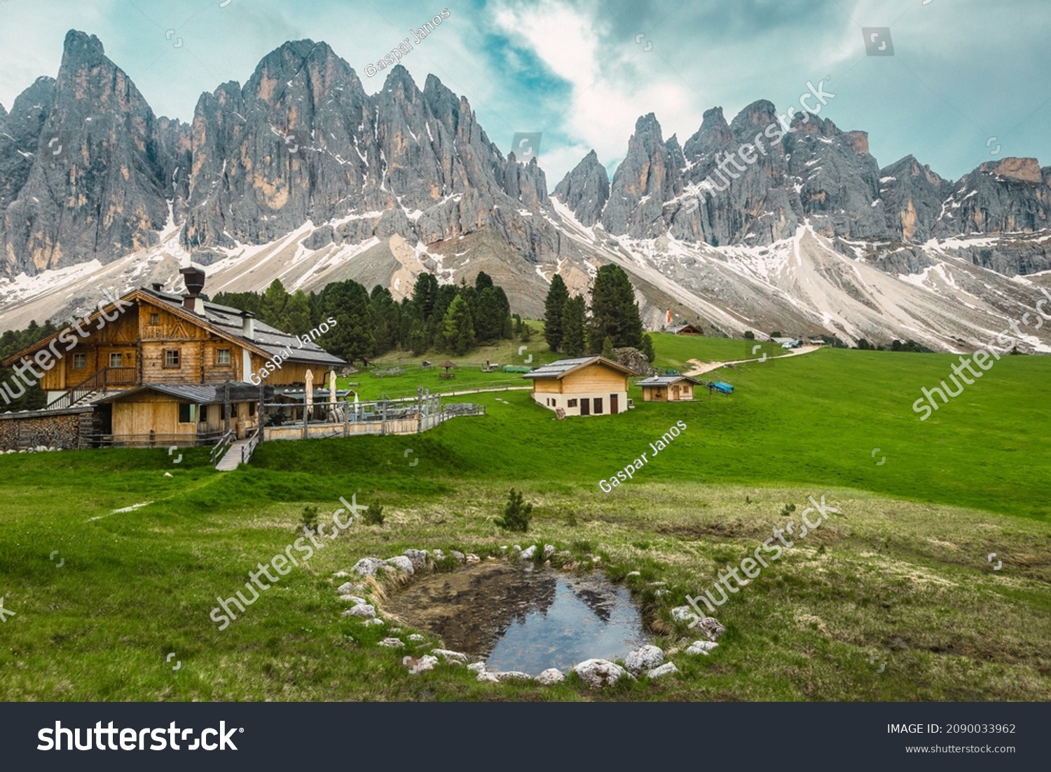 Majestic spring alpine landscape, wooden houses on the green fields and small lake with mountains in background, Geisler - Odle mountain group, Alto Adige, Dolomites, Italy, Europe #2090033962
