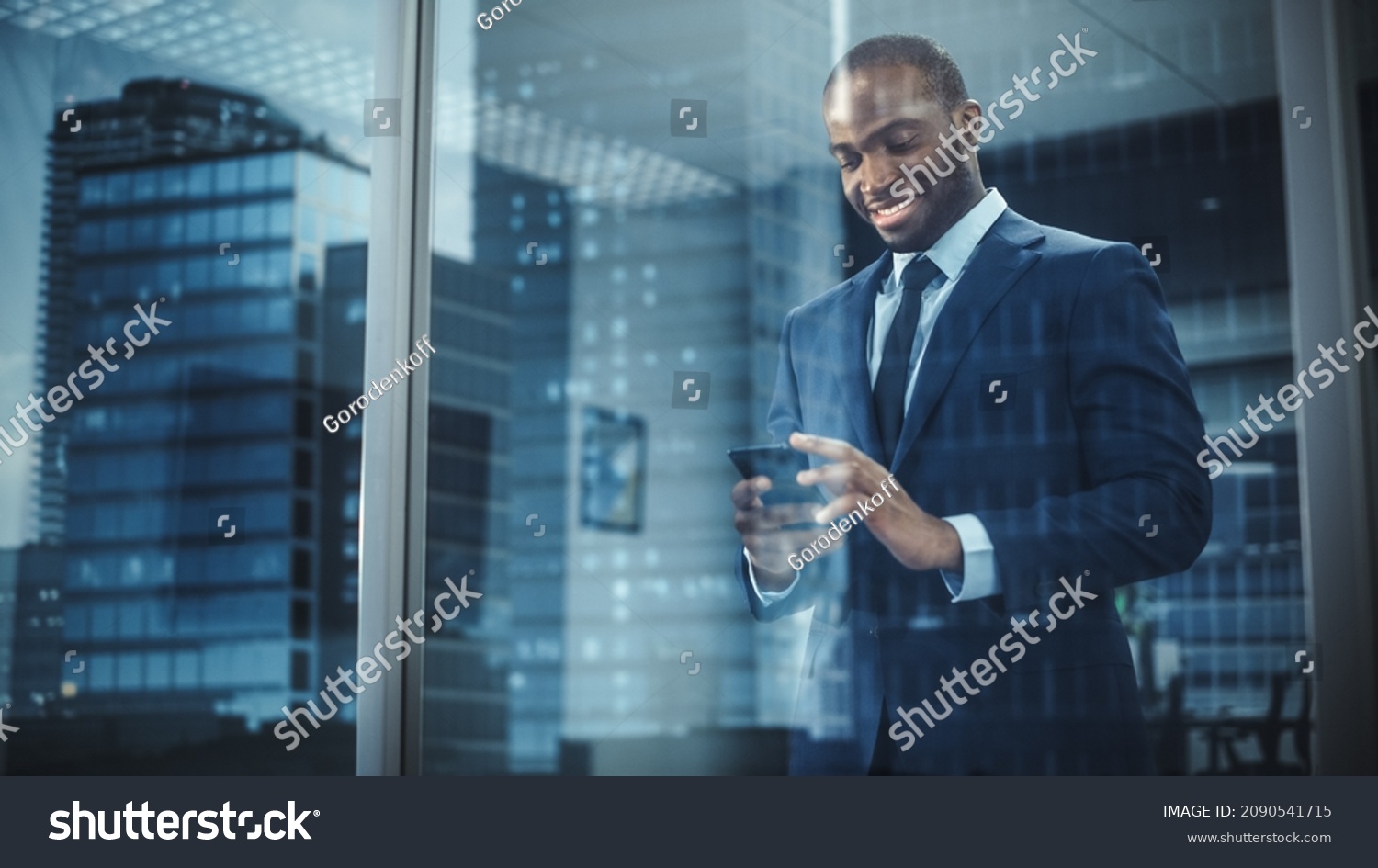 Portrait of Successful Black Businessman Wearing Suit Standing, Using Smartphone Looking out of the Window. Successful African CEO Planning e-Commerce Investment Strategy. From Outside Shot #2090541715